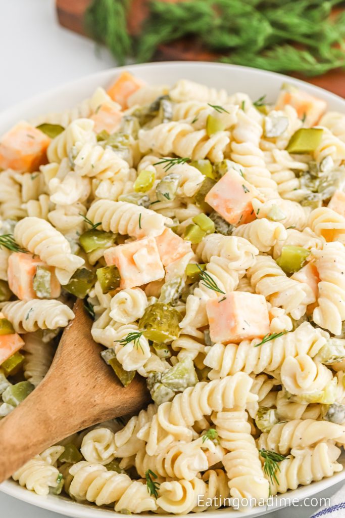 Dill Pickle Pasta Salad in a bowl with a wooden spoon