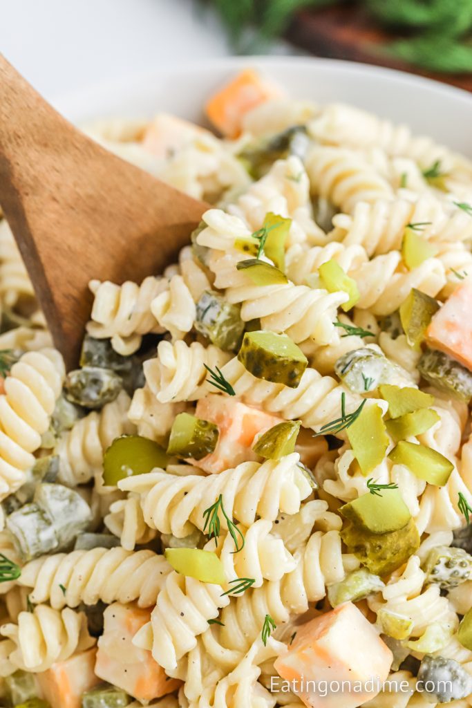 Dill Pickle Pasta Salad in a bowl with a wooden spoon