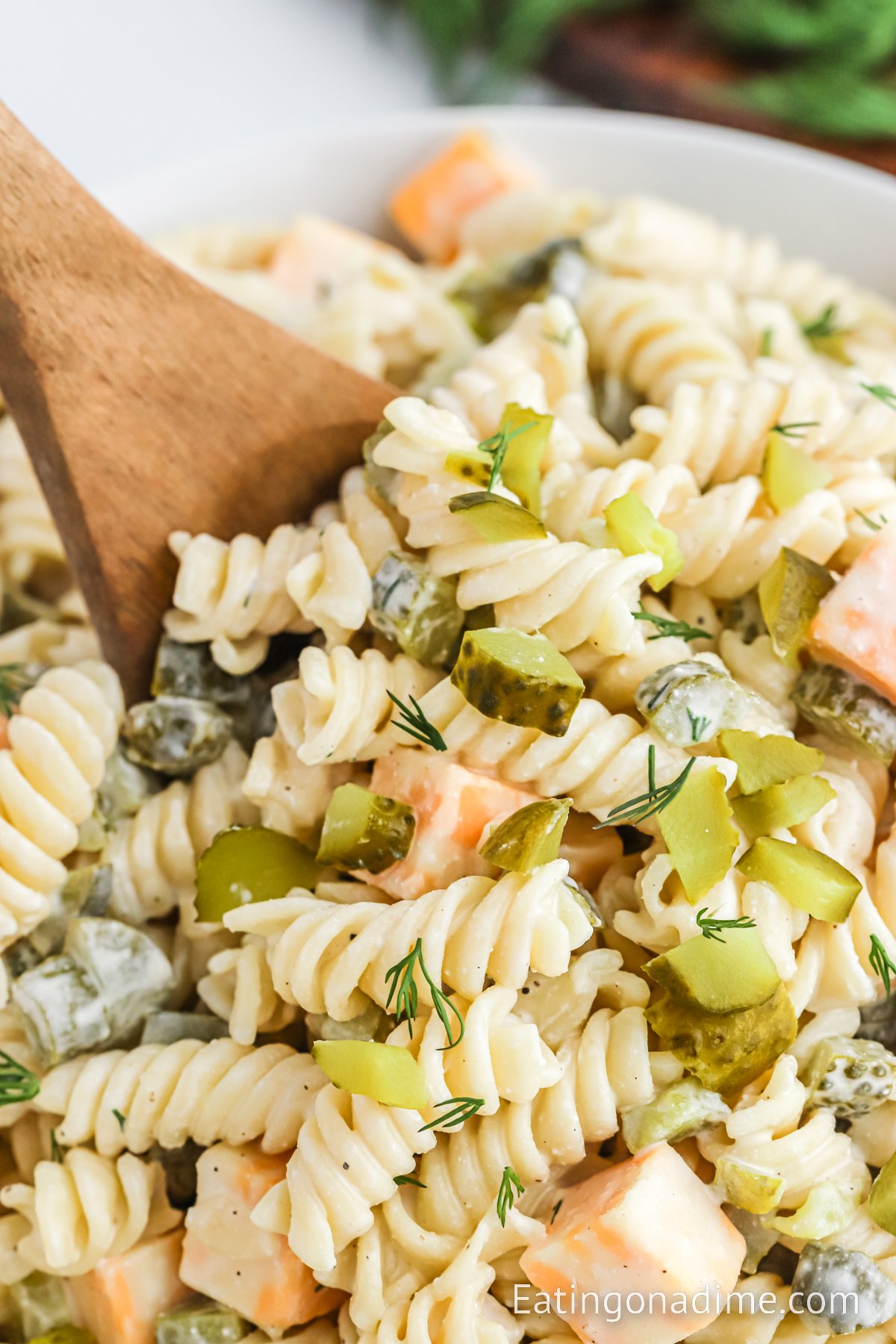 Dill Pickle Pasta Salad in a bowl with a wooden spoon