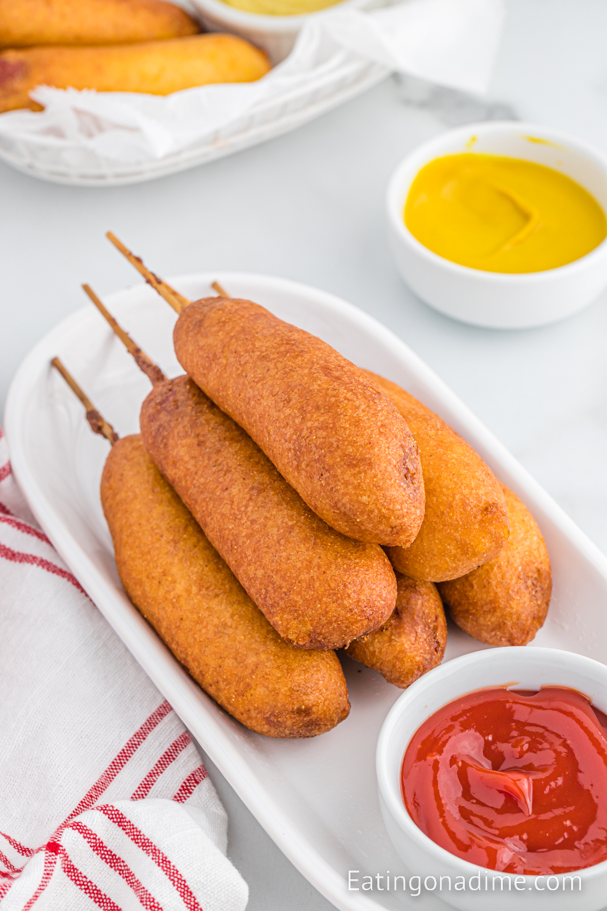 Corndog stacked on a platter with a bowl of ketchup