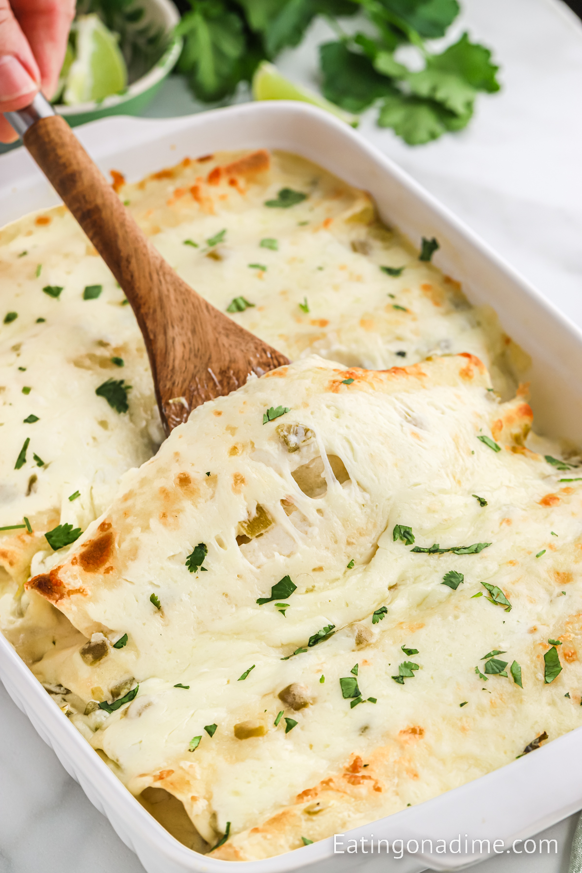 White Chicken Enchilada in a casserole dish with a wooden spoon