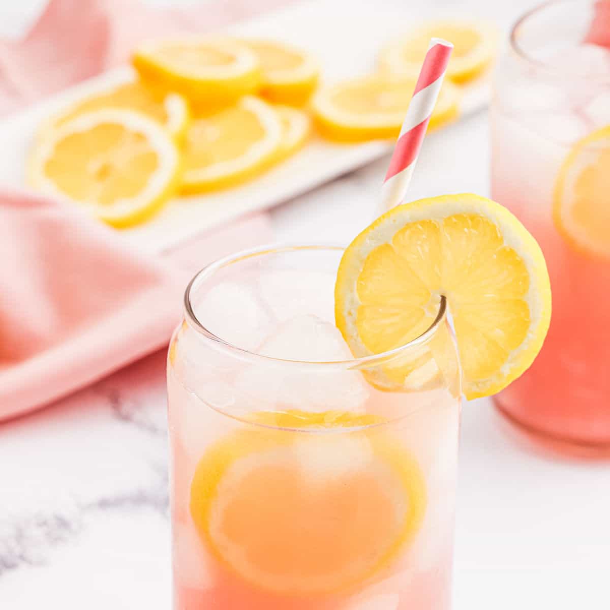 Pink Lemon in a clear glass garnished with a lemon slice.