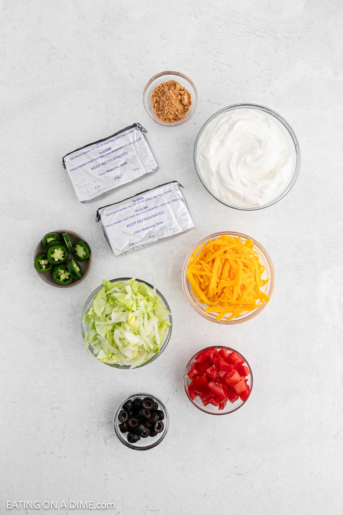 Ingredients - Cream cheese, sour cream, taco seasoning, cheese, lettuce, tomato, black olives, jalapenos