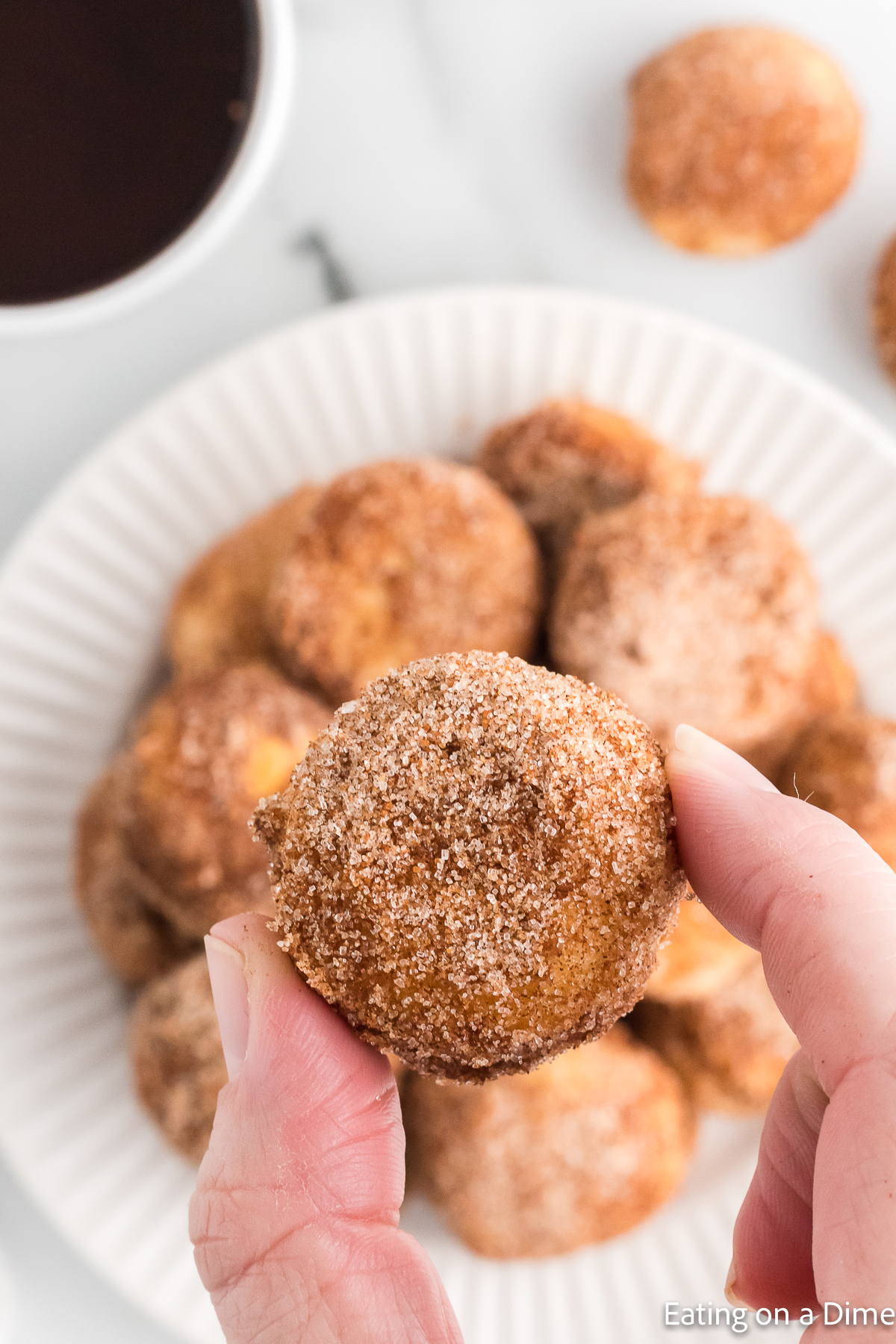 Cinnamon Sugar Donut Holes on a white plate with a close up of one 