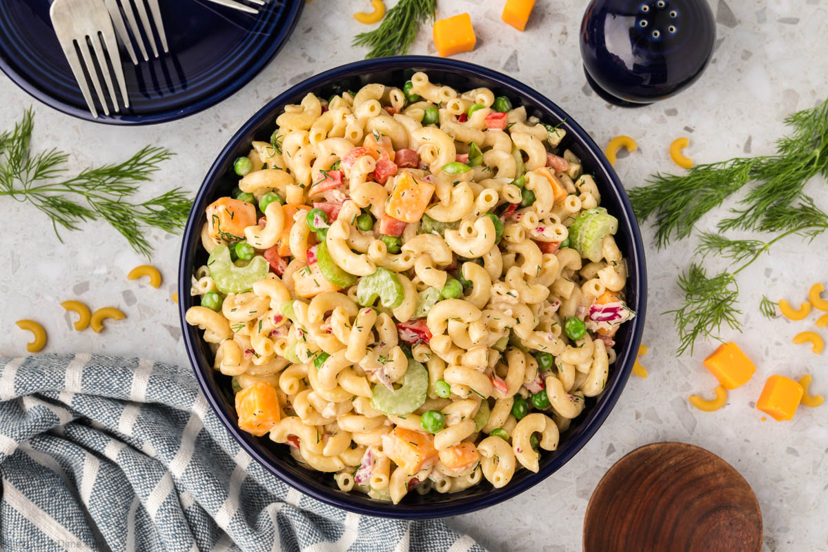 Close up of creamy Macaroni Salad in a large bowl topped with fresh dill 