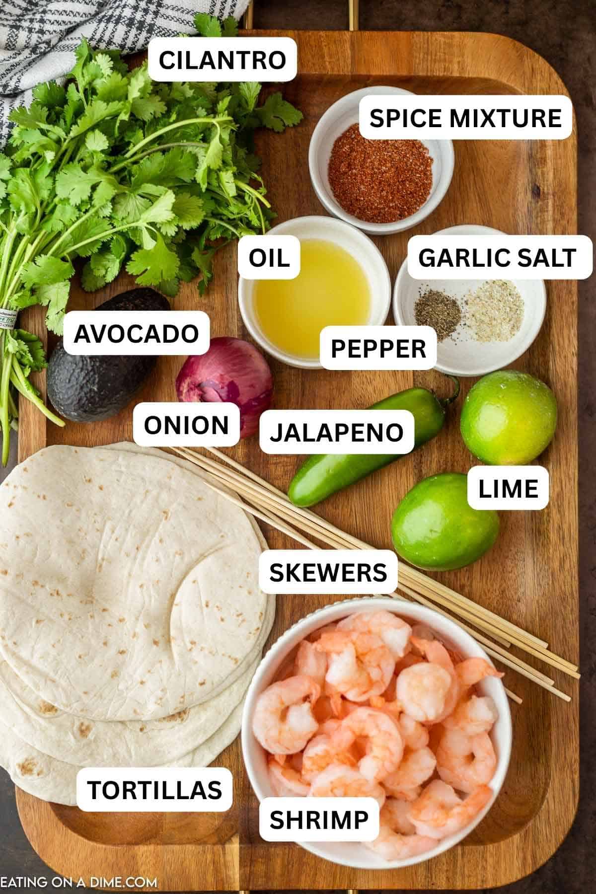 Ingredients needed to make this recipe which includes shrimp, olive oil, chili powder, cumin, garlic powder, lime, avocado, red onion, jalapeno, cilantro, lime, garlic salt, pepper, skewers, flour tortilla, and cojita cheese.