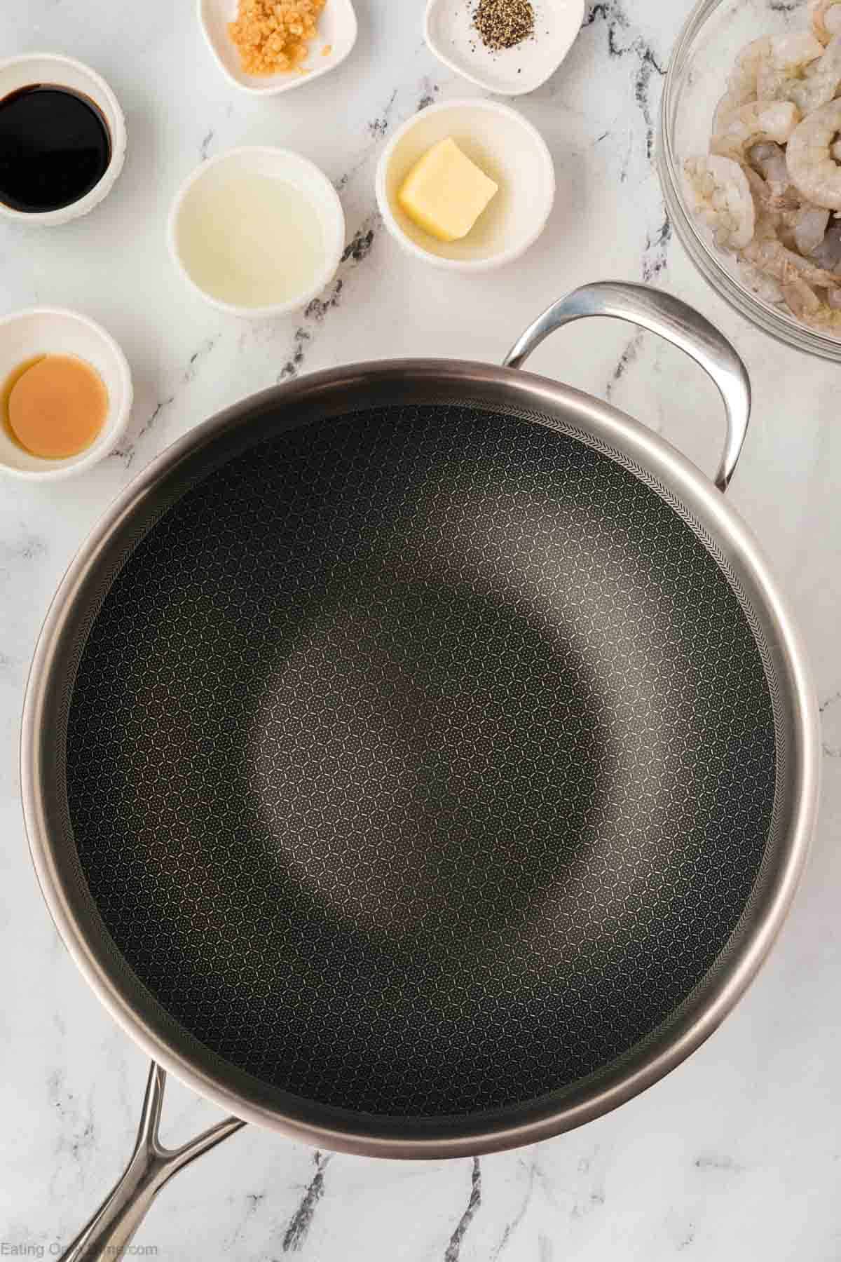 Large skillet with small bowls of butter, oil, and spices on the side