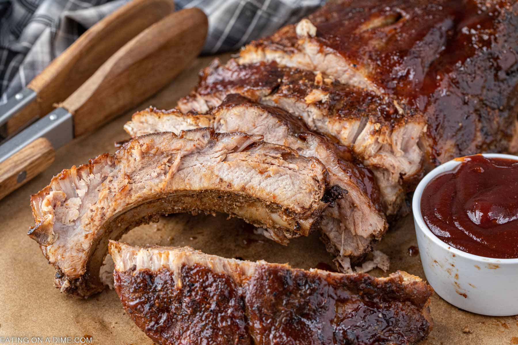 Baby back ribs slice on a platter with a side of BBQ Sauce