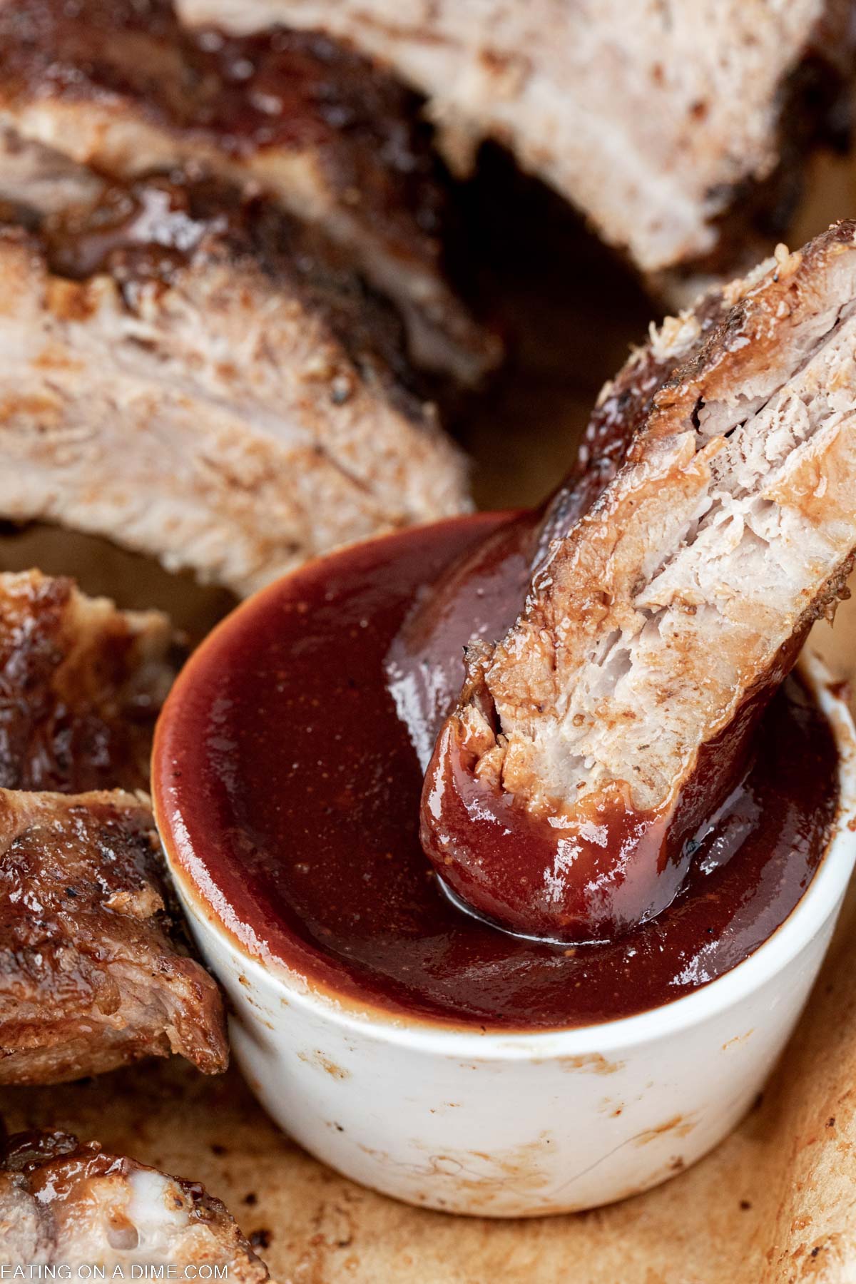 Dipping baby back ribs in BBQ sauce