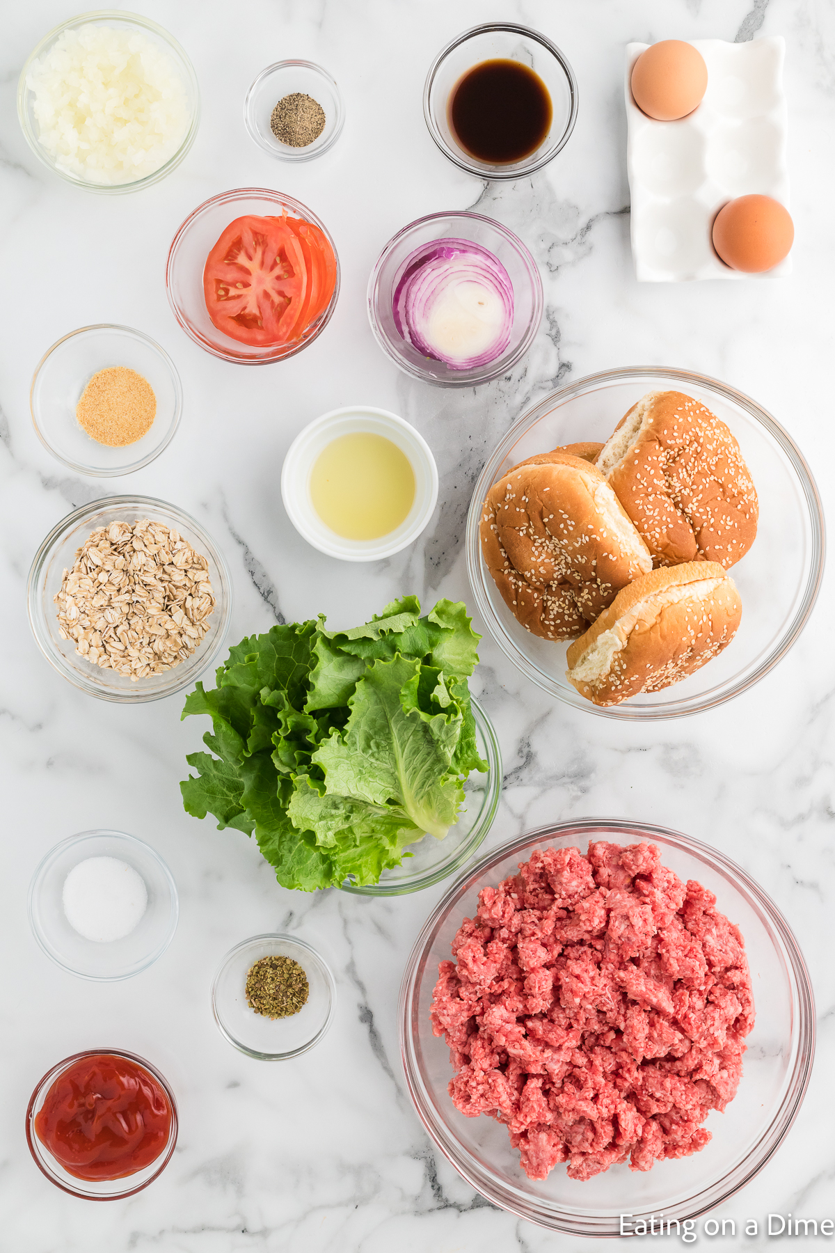 Ingredients for Meatloaf burgers. Ground beef, quick oats, eggs, onion, worcestershire sauce, ketchup, oregano, garlic powder, salt, pepper, buns, lettuce, tomato, red onion
