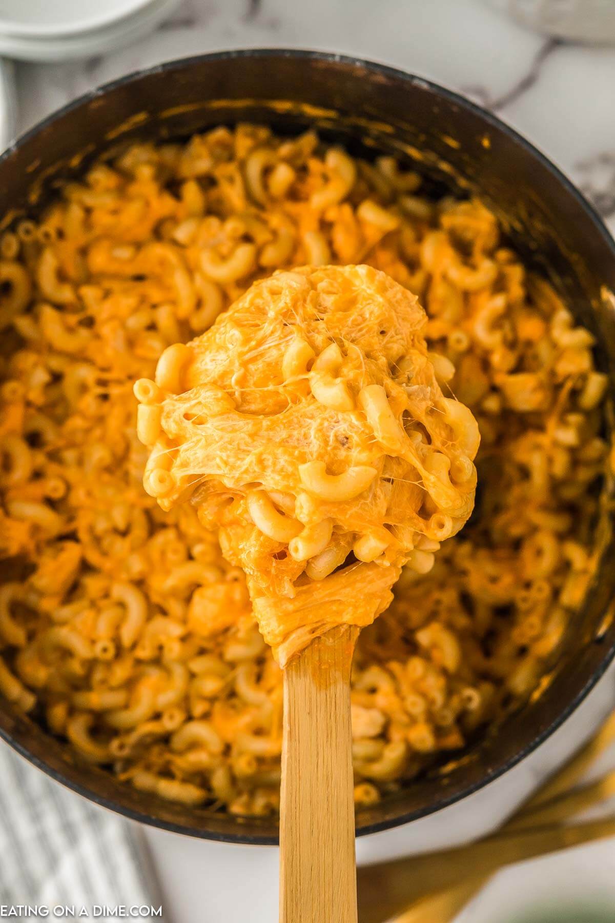Buffalo Chicken Mac and Cheese in a large skillet with a serving on the wooden spoon