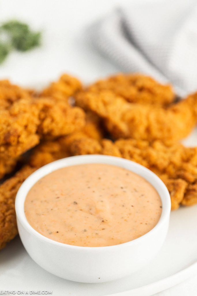 Close up image of chicken fingers and a bowl of chicken dipping sauce