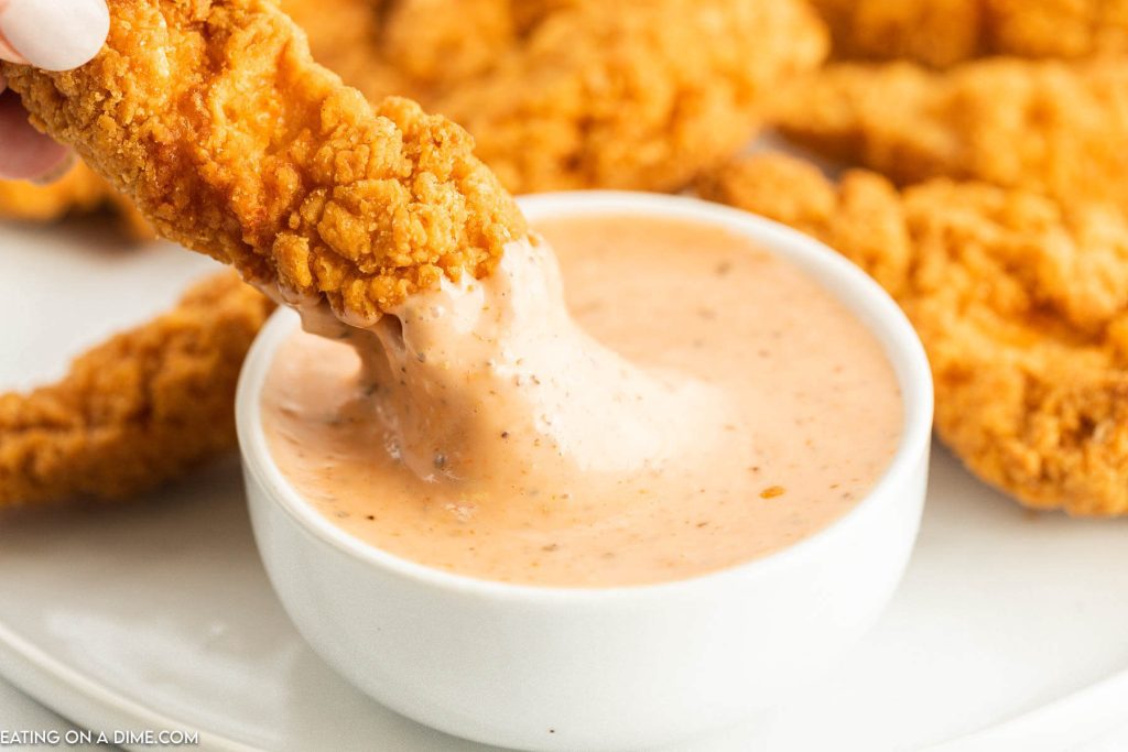Close up image of chicken fingers and a bowl of chicken dipping sauce with a chicken finger dipping sauce