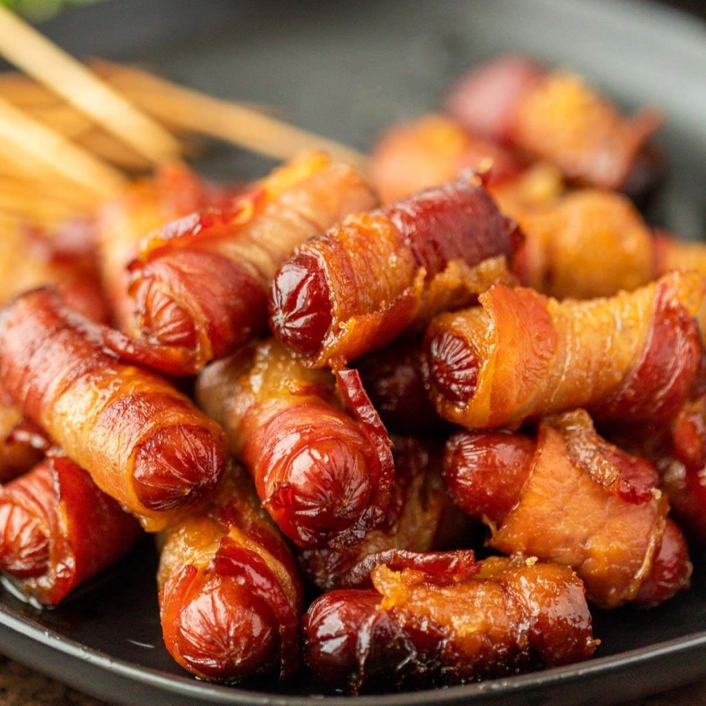 Bacon wrapped lil smokies stacked on a platter