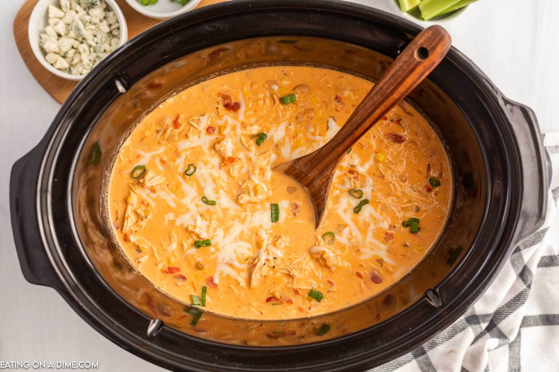 Buffalo Chicken Chili in the slow cooker with a wooden spoon