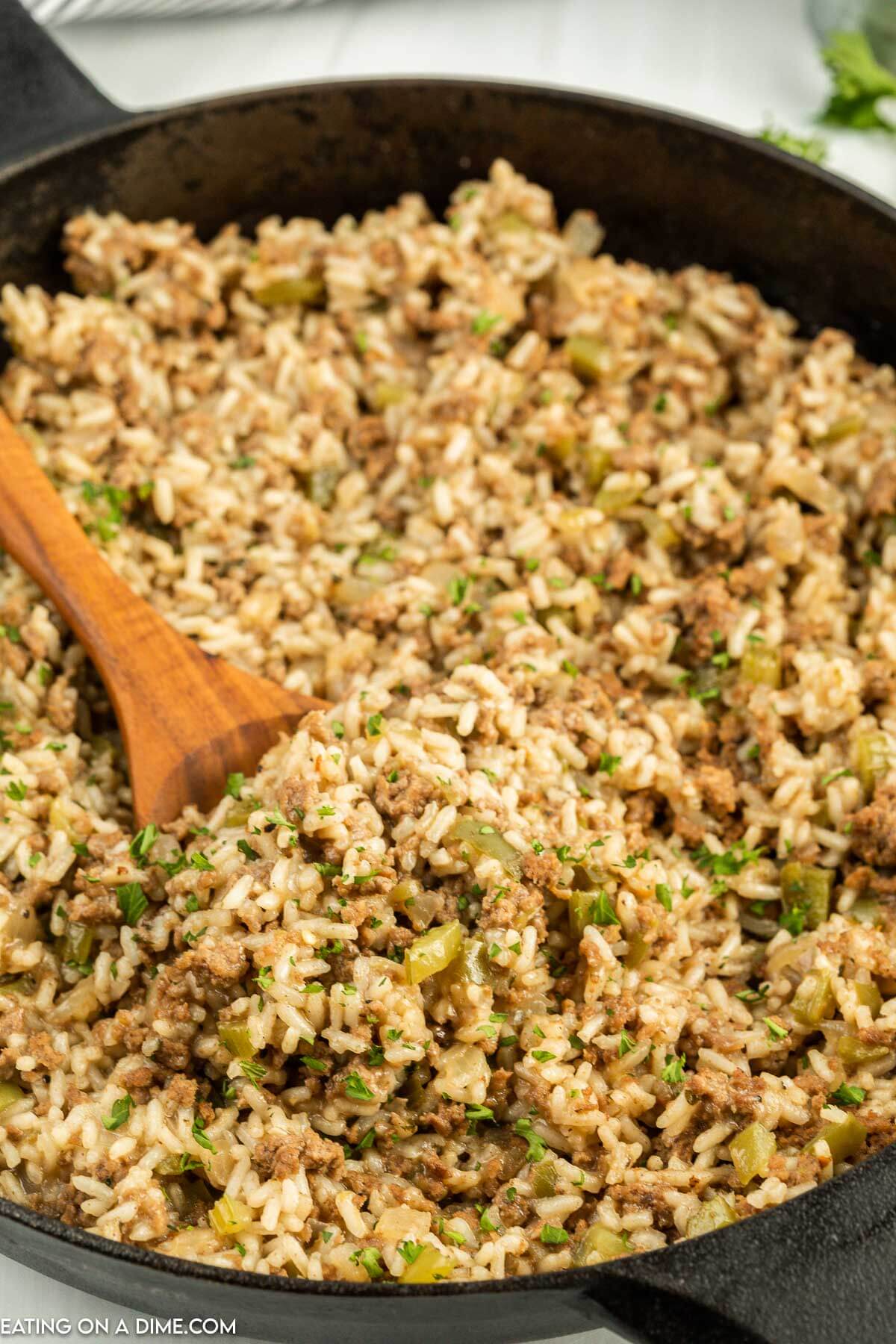 Dirty Rice in a skillet with a wooden spoon