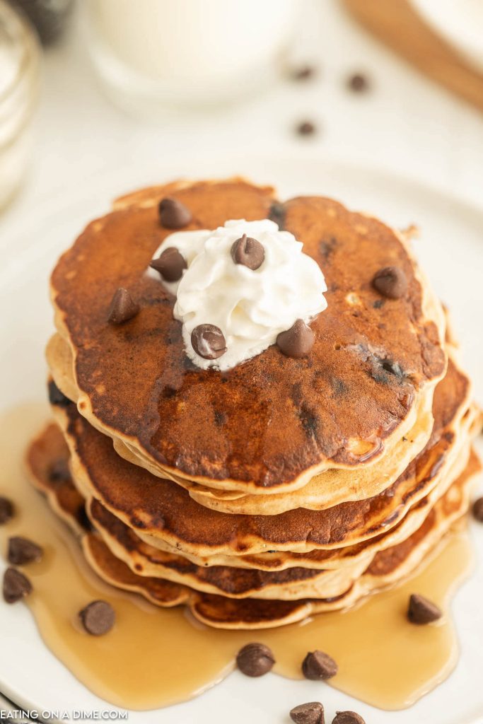 Chocolate Chip Pancakes stacked with syrup, whipped cream and chocolate chips