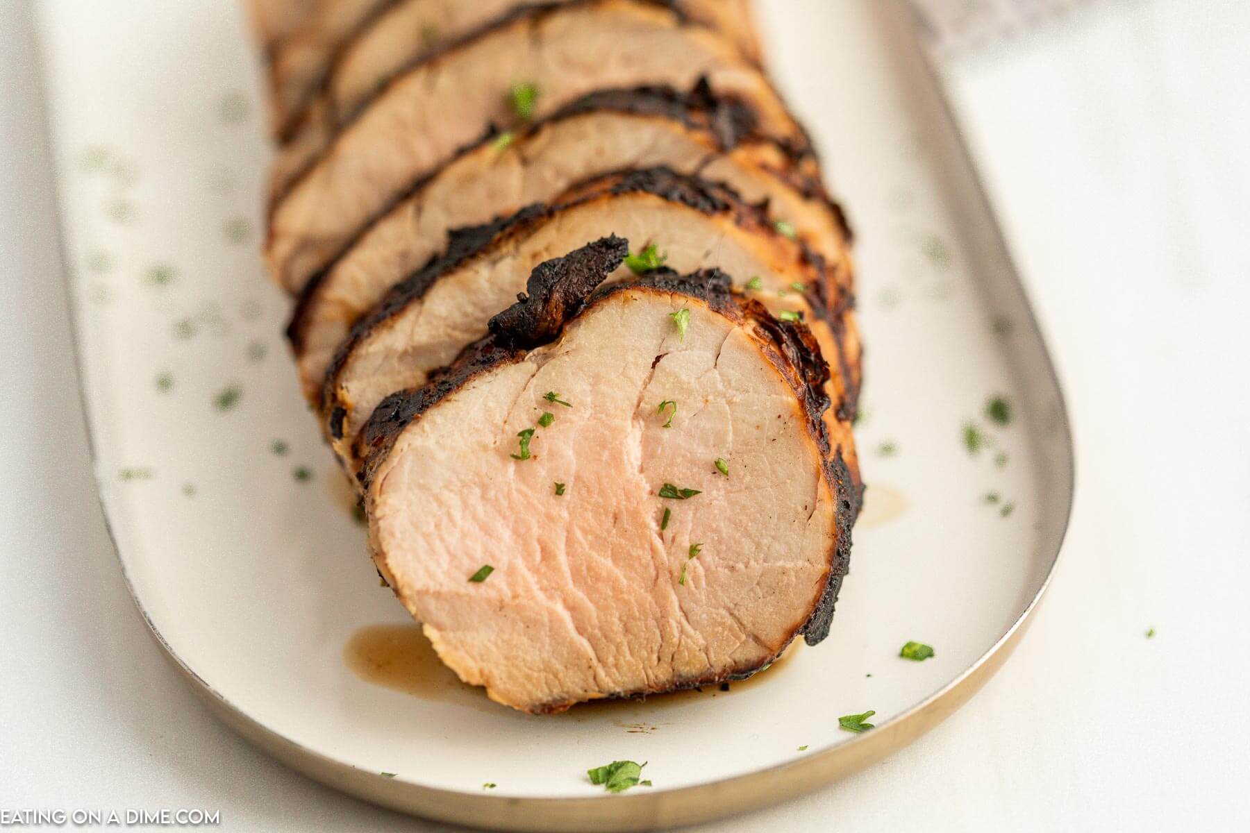 Grilled pork tenderloin sliced on platter. 