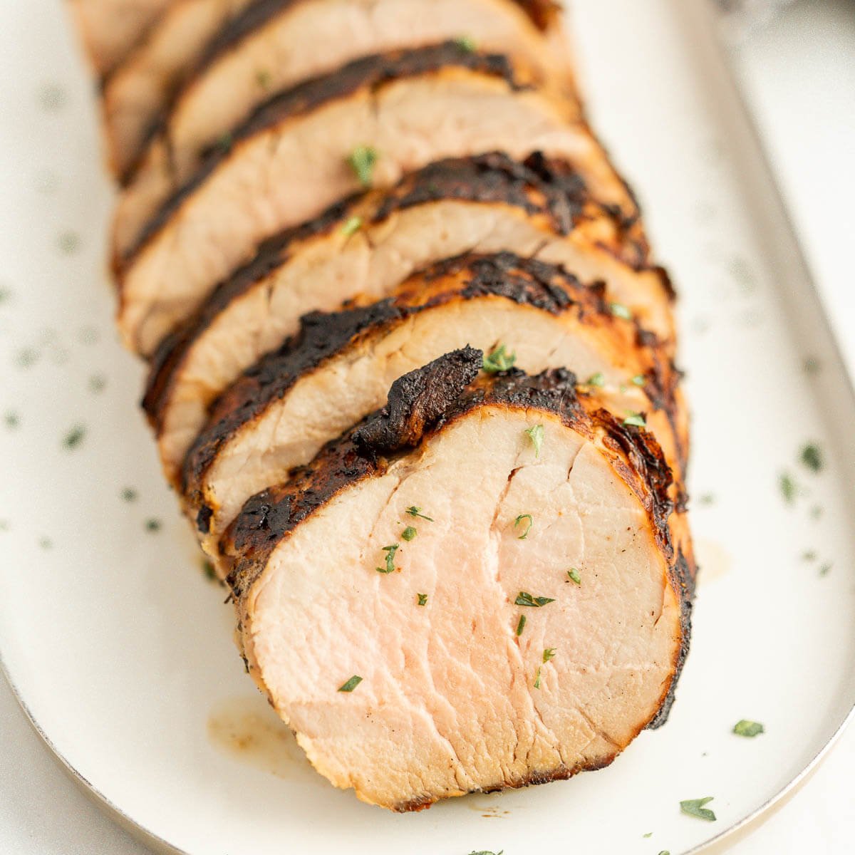 Grilled pork tenderloin sliced on platter. 