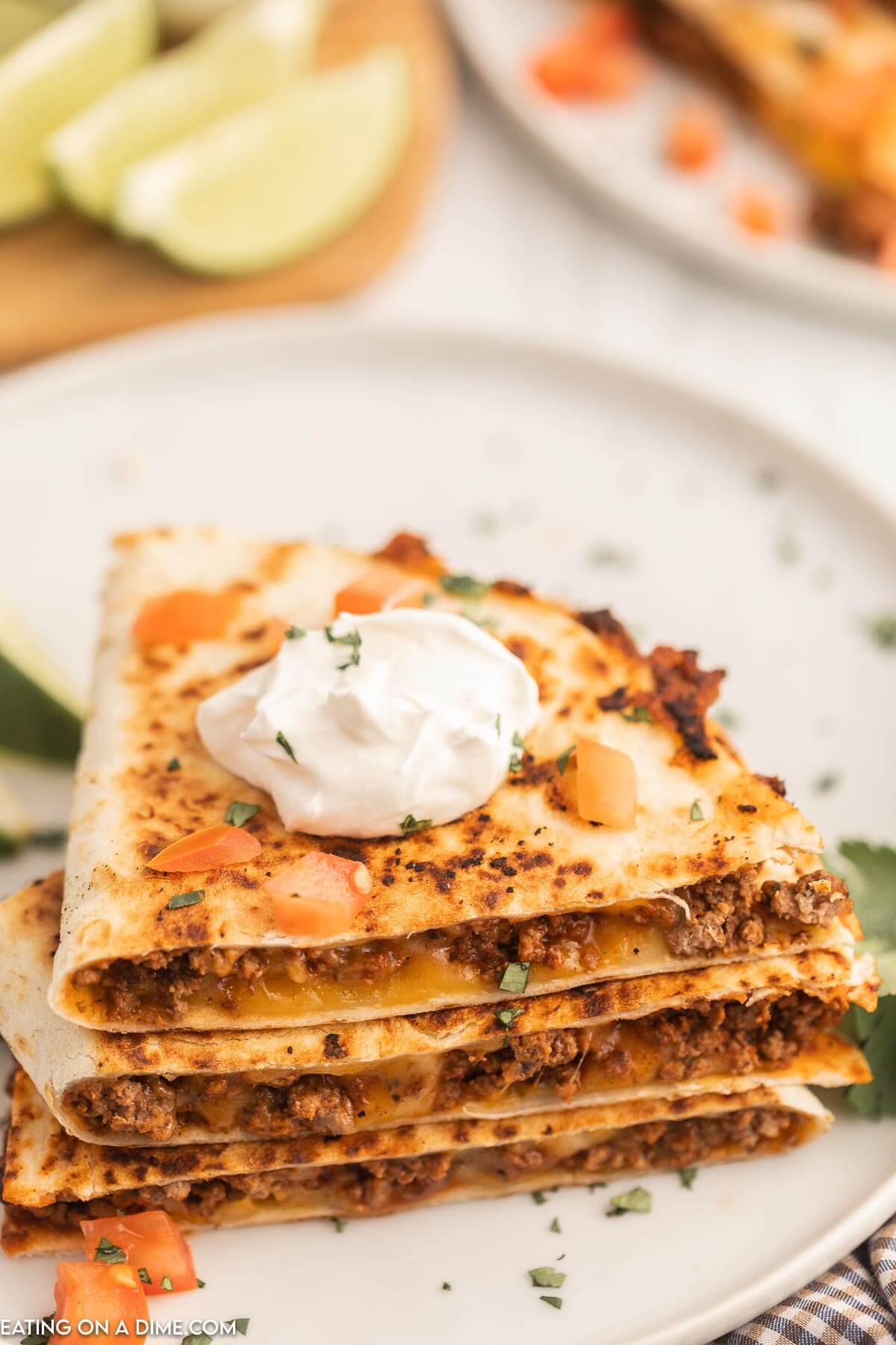 Cheesy Beef Quesadillas stacked and topped with sour cream