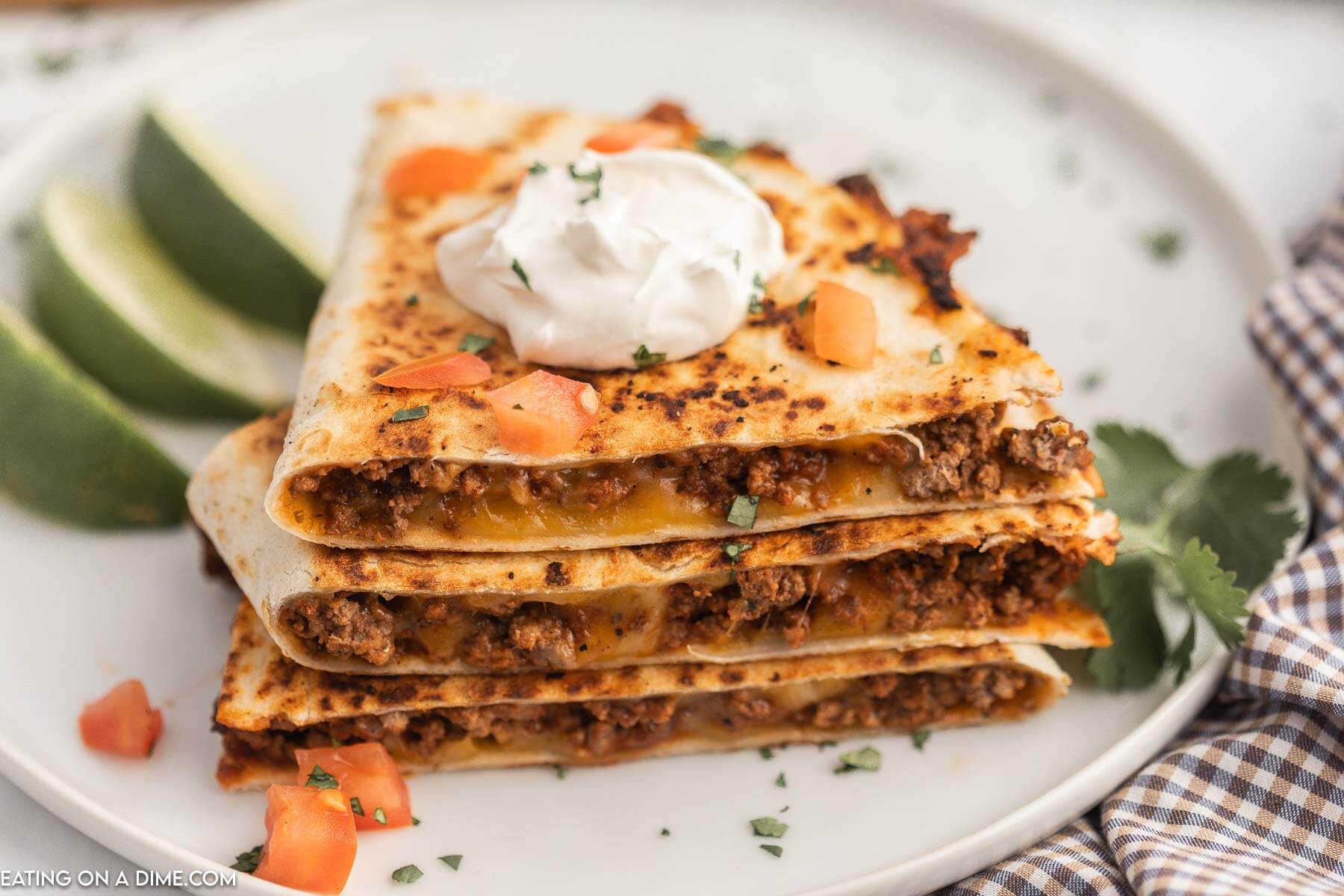 Cheesy Beef Quesadillas stacked and topped with sour cream