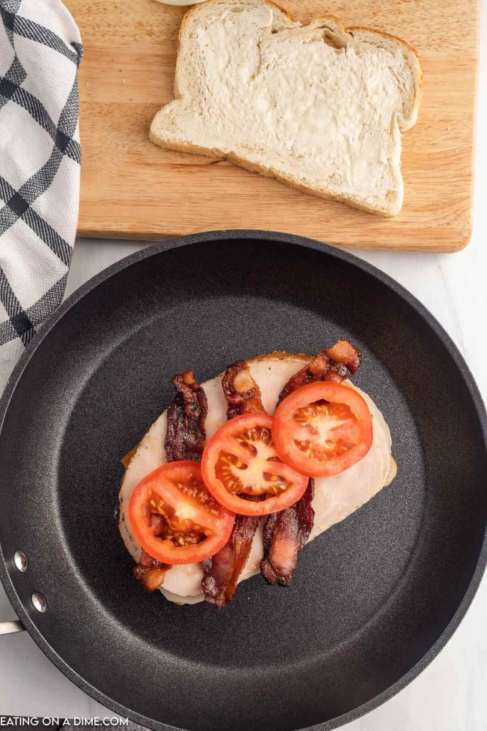 Bread, turkey, bacon and tomato in a skillet