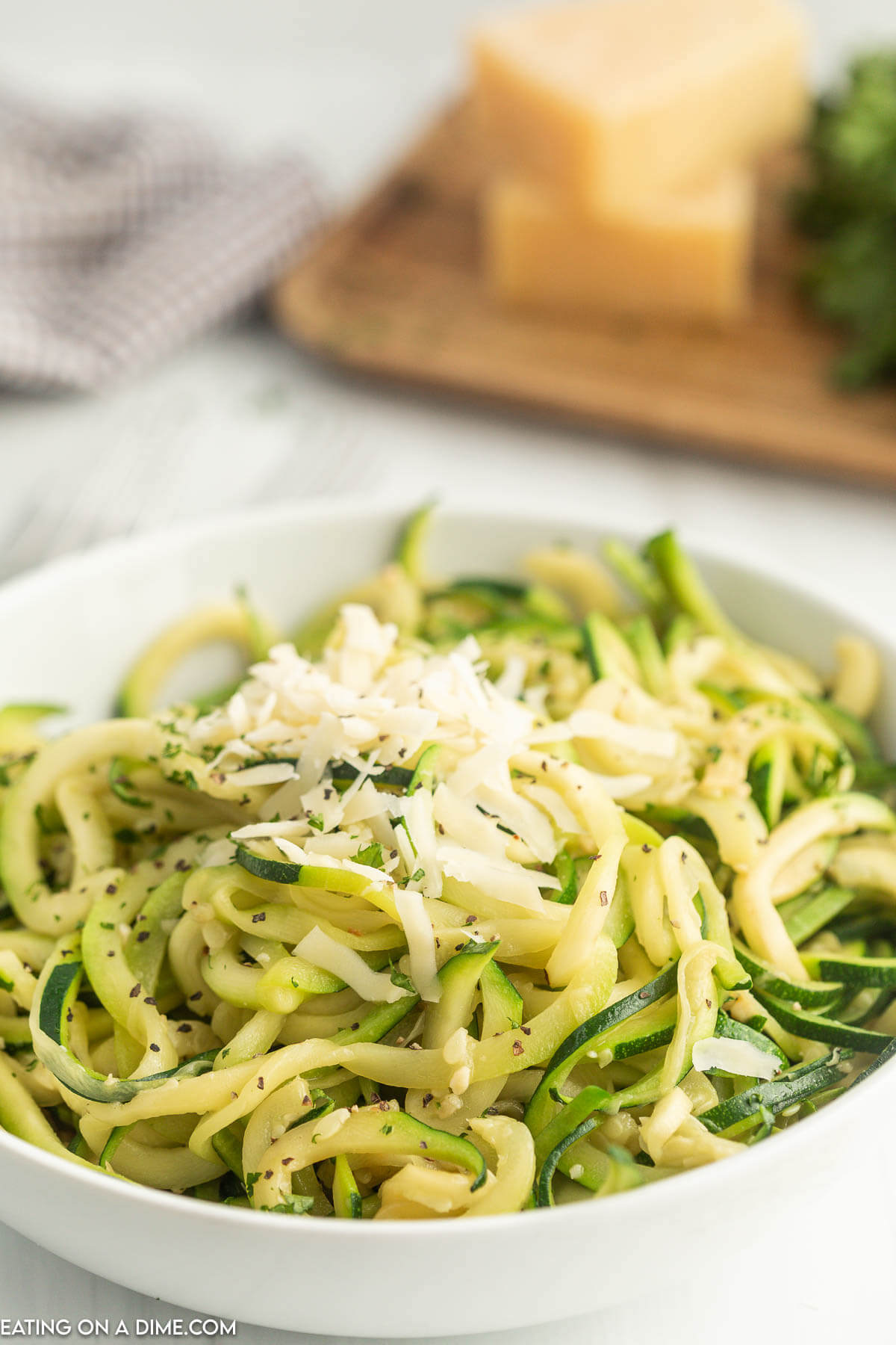 If you're looking for a healthy but yummy side dish, try Zucchini Noodles Recipe. Not only is this a tasty option, it is so easy to make this zoodle recipe. Zucchini Noodles topped with mozzarella cheese in a white bowl