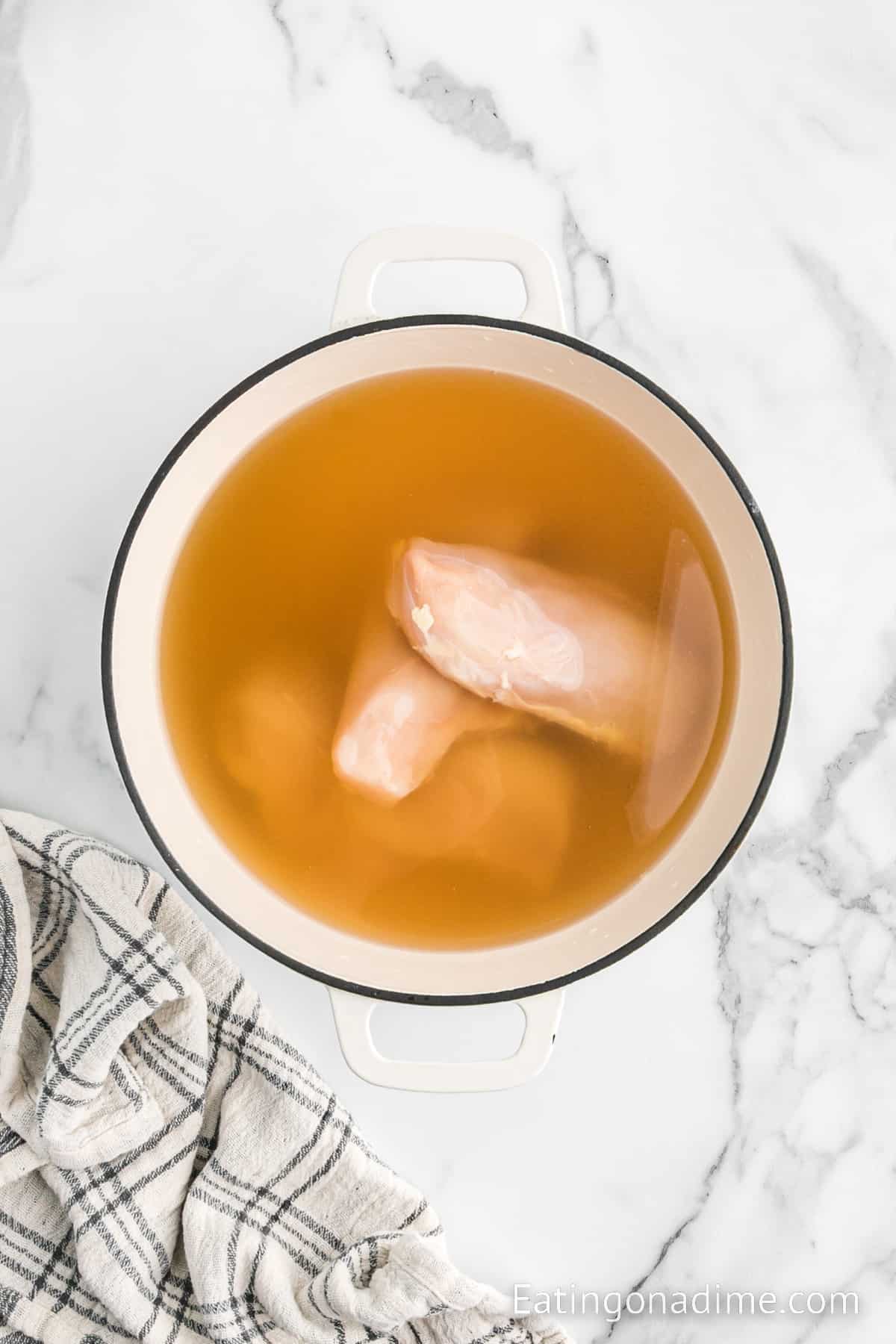 Chicken breast in a large pot with chicken broth and water