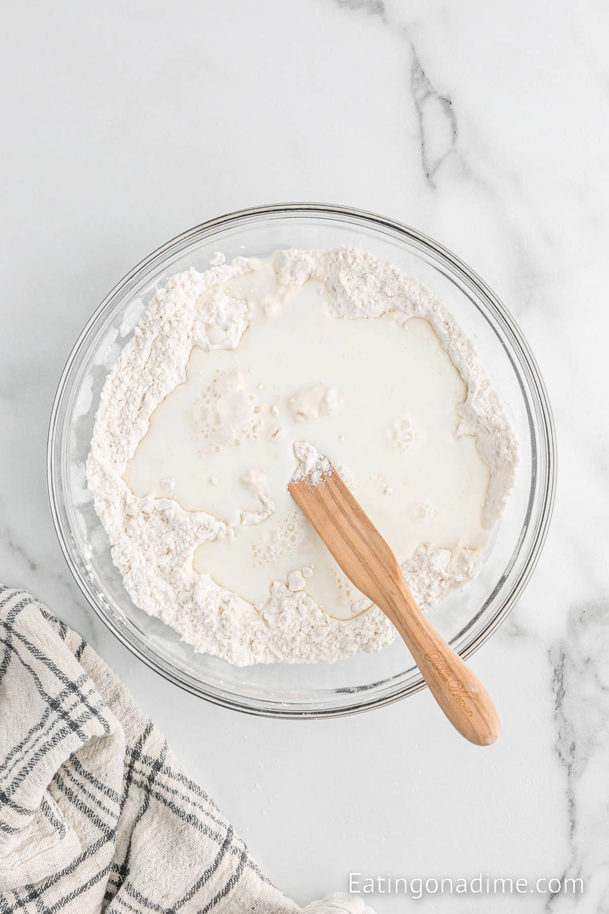 Combining flour, baking powder, and salt in a bowl with the butter and milk with a wooden spoon