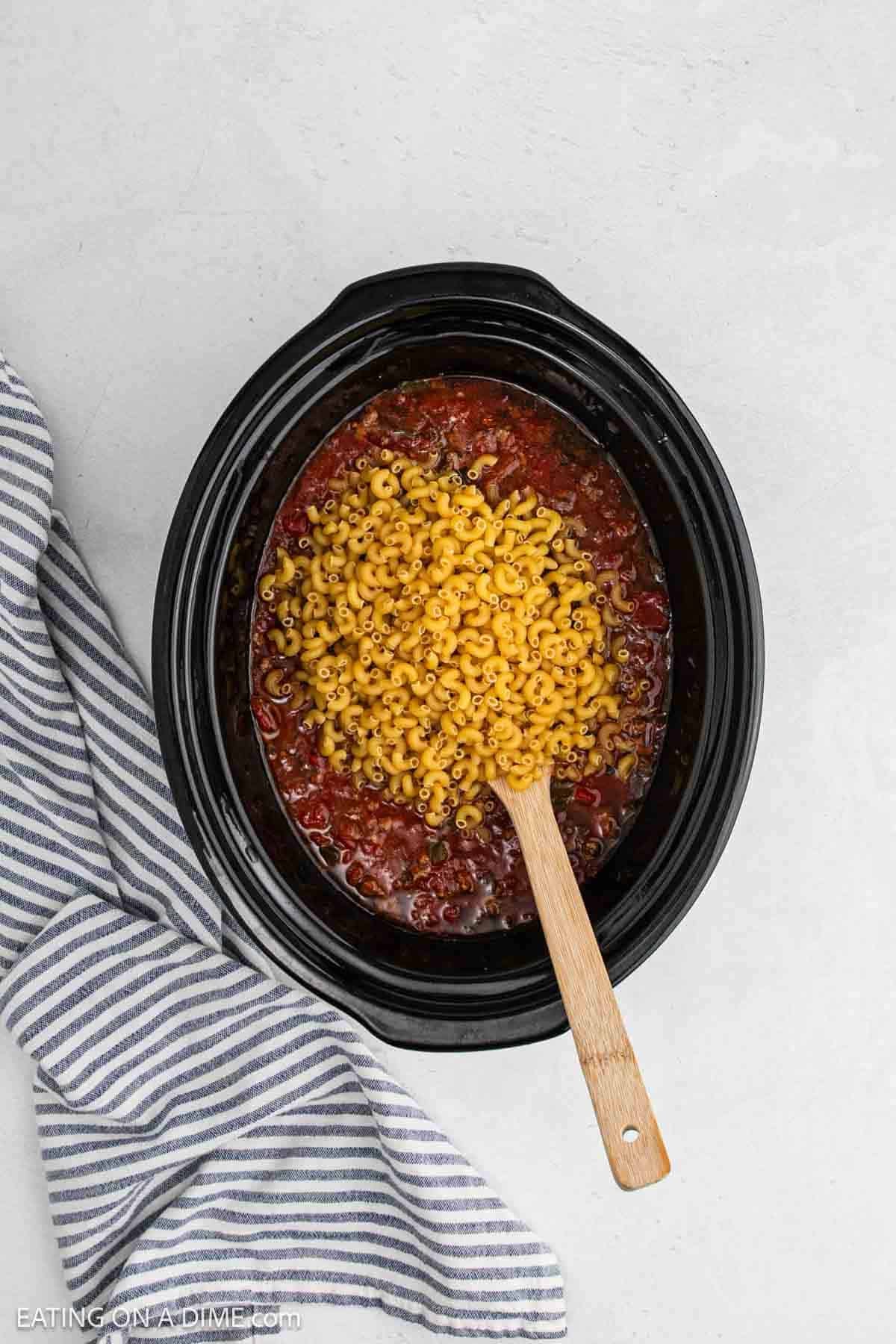 Macaroni noodles added to the slow cooker with the cooked ingredients.