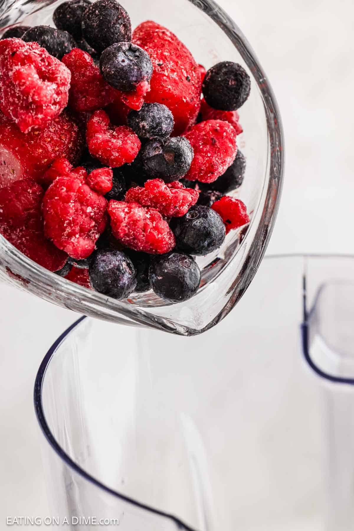 Pouring in frozen fruit into blender.