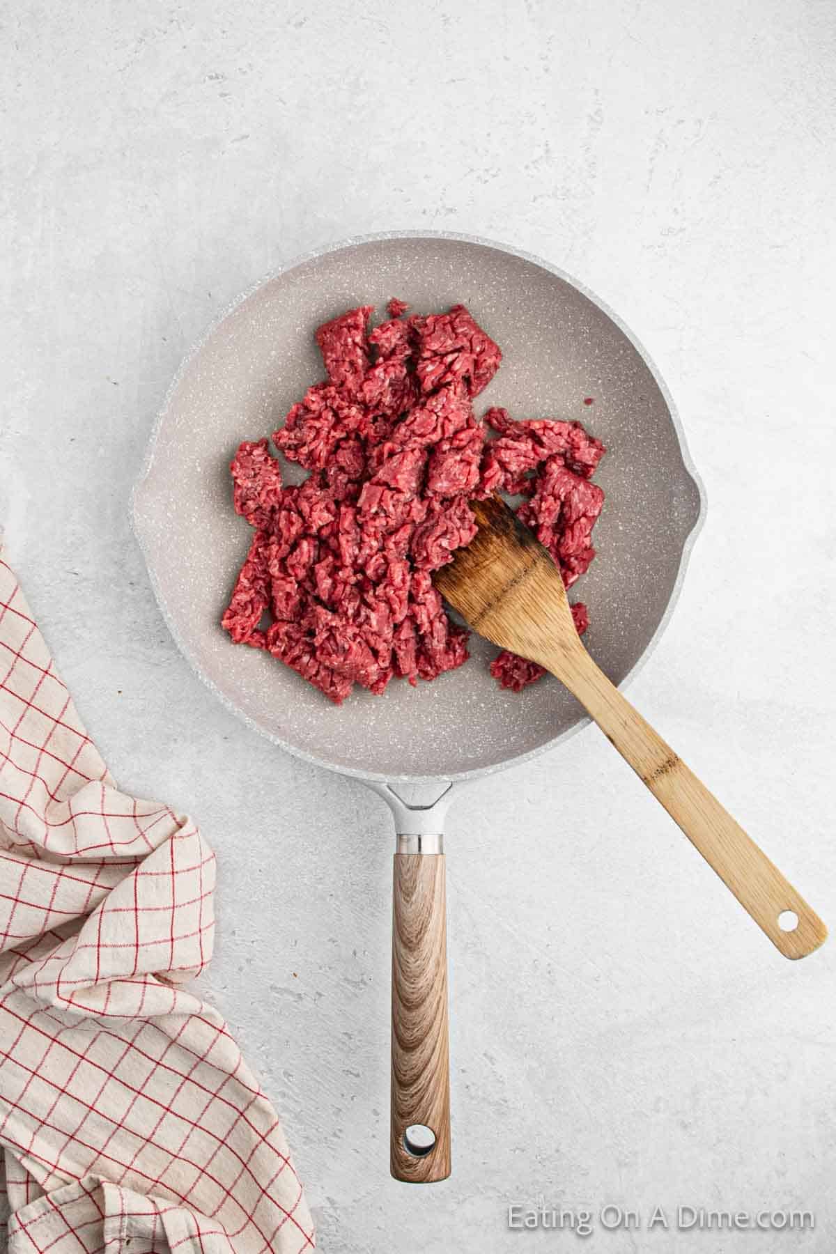 Ground beef in a skillet with a wooden spoon