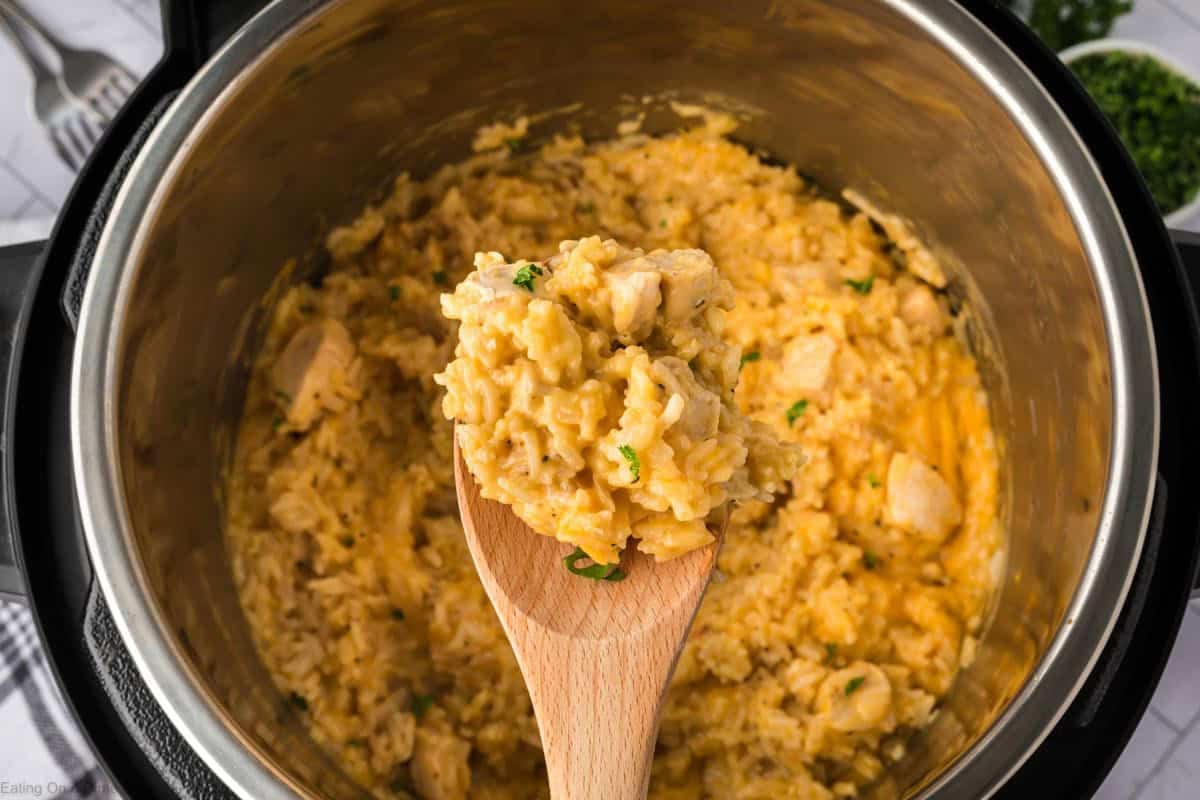 Cheesy, chicken and rice in the instant pot with a wooden spoon