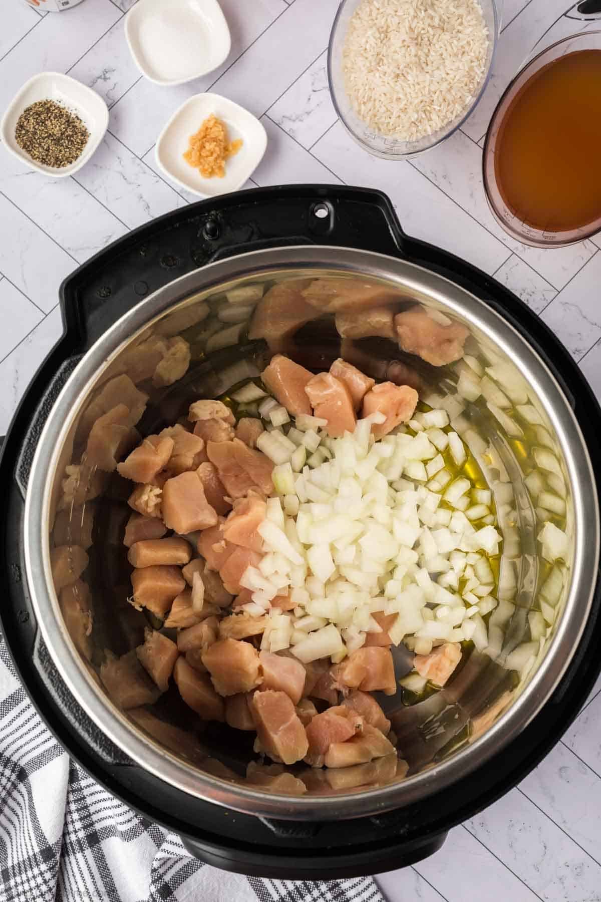 Diced raw chicken with chopped onions and oil in the instant pot