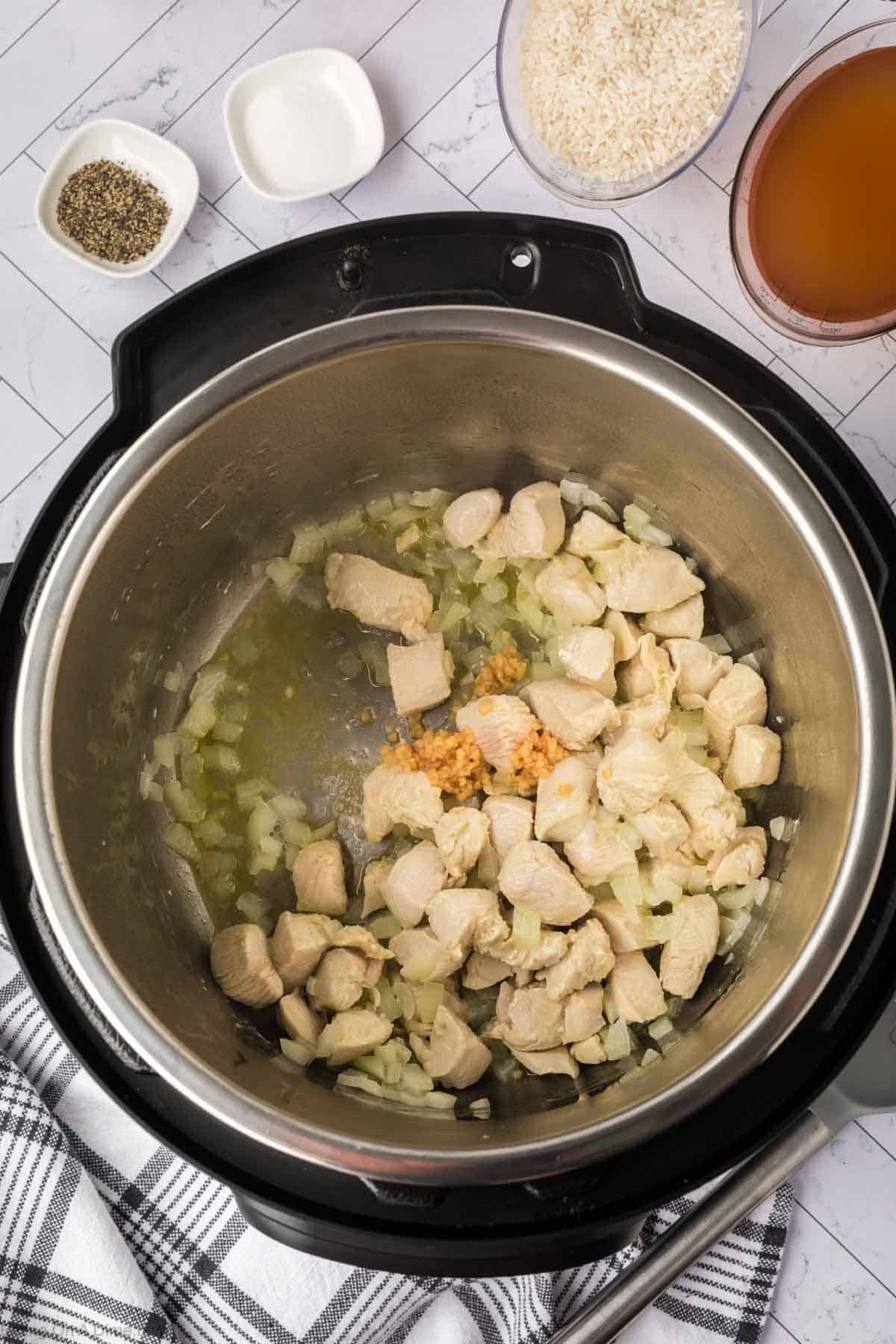 cooked chicken in the instant pot with cooked onions and minced garlic