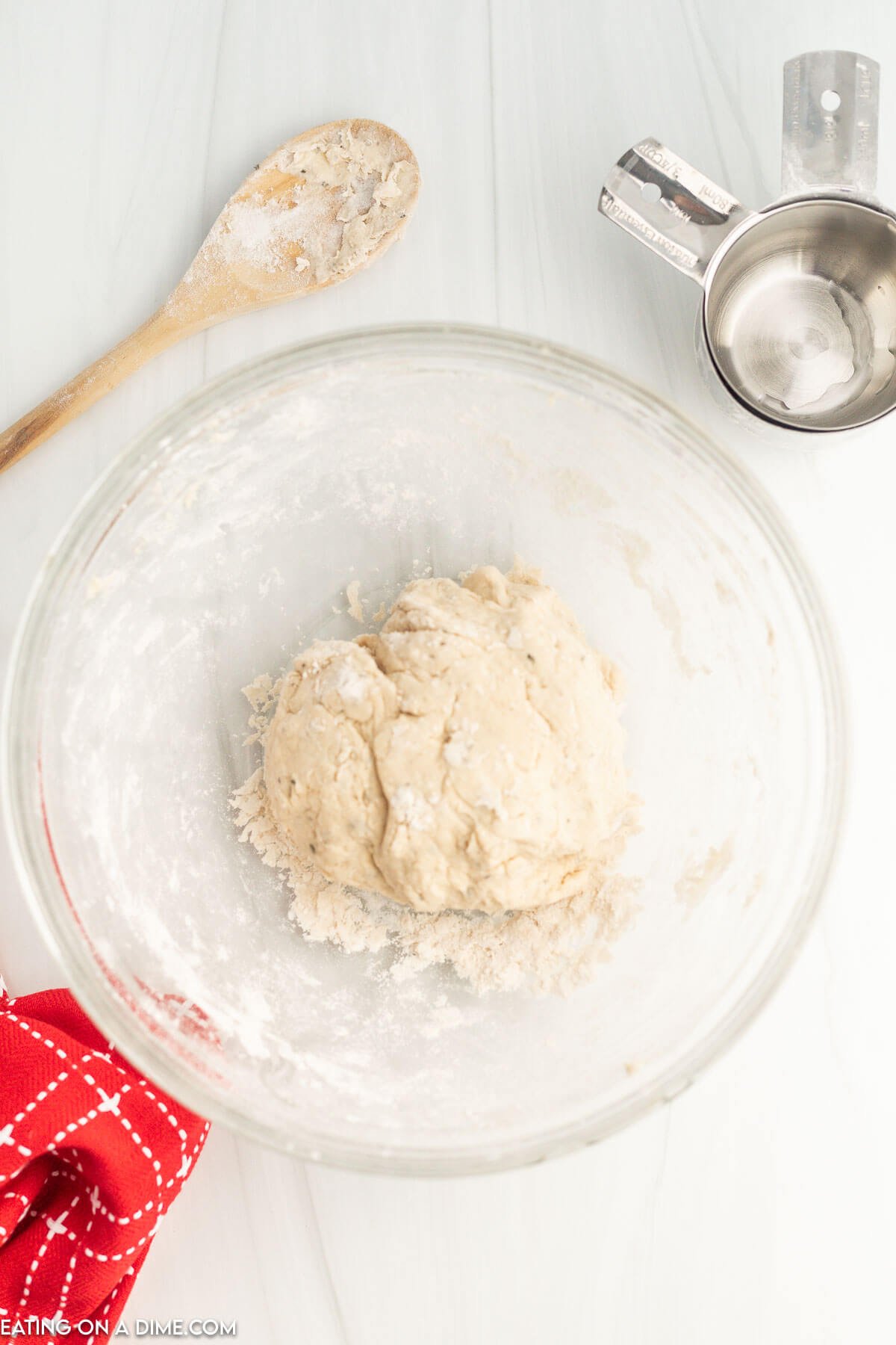 Dough formed into a ball in a bowl with a wooden spoon on the side