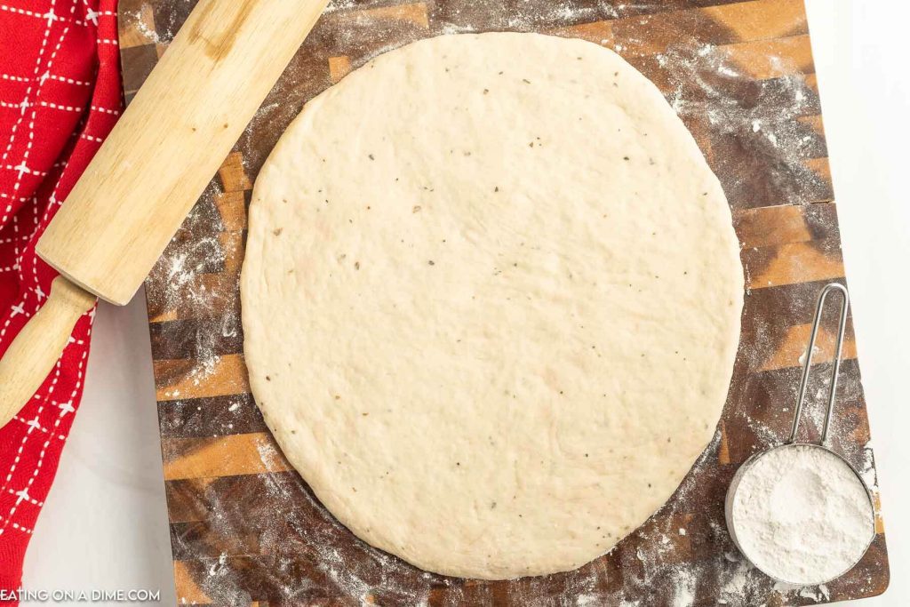 Homemade crust on a floured surface with a rolling pin