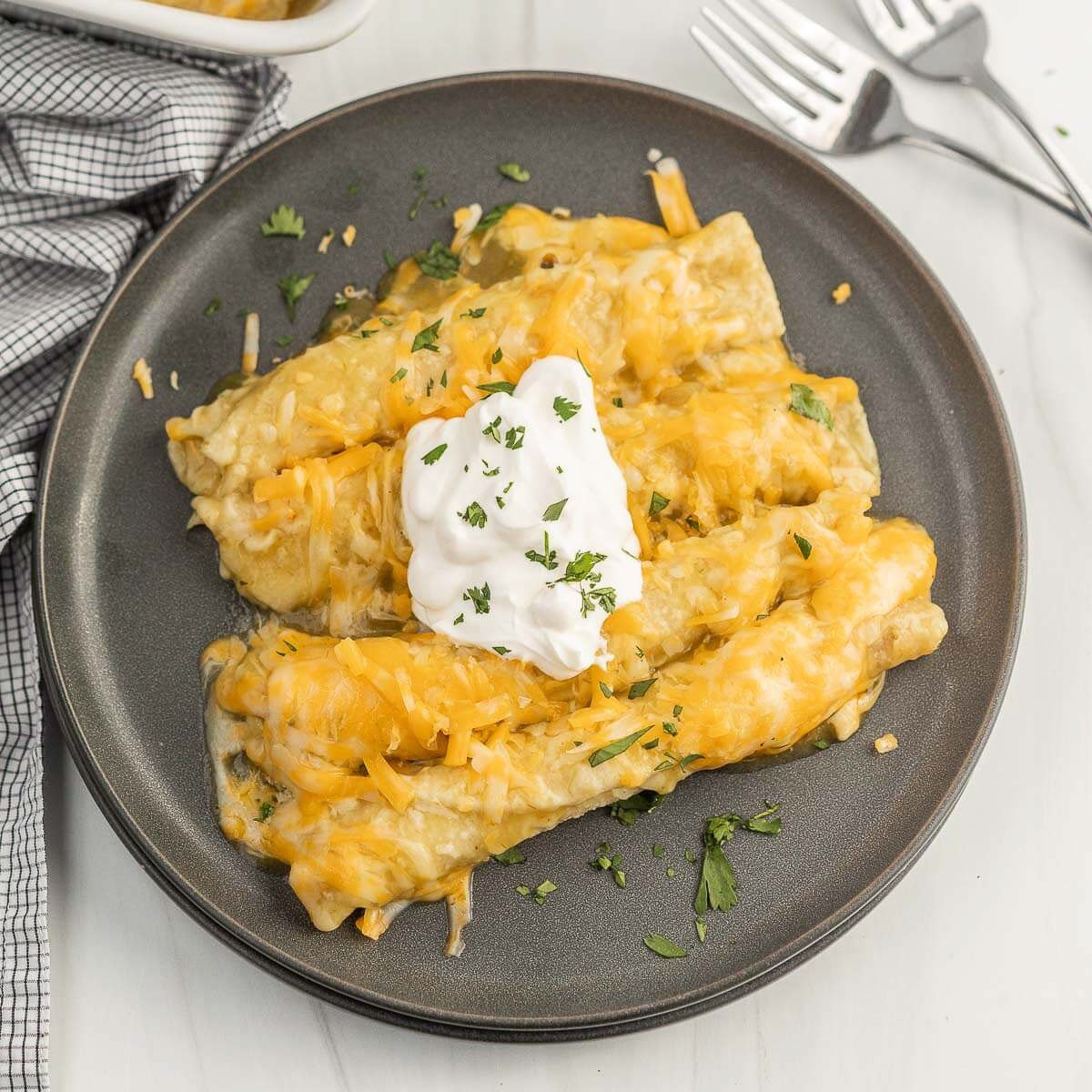 Taquito Enchiladas on a plate topped with sour cream