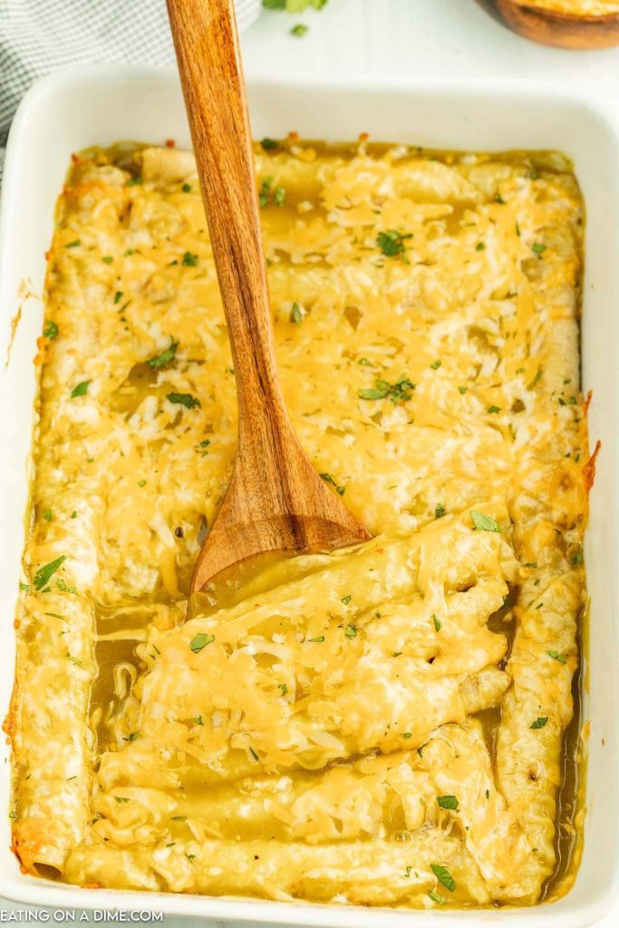 enchiladas in a baking dish with a wooden spoon