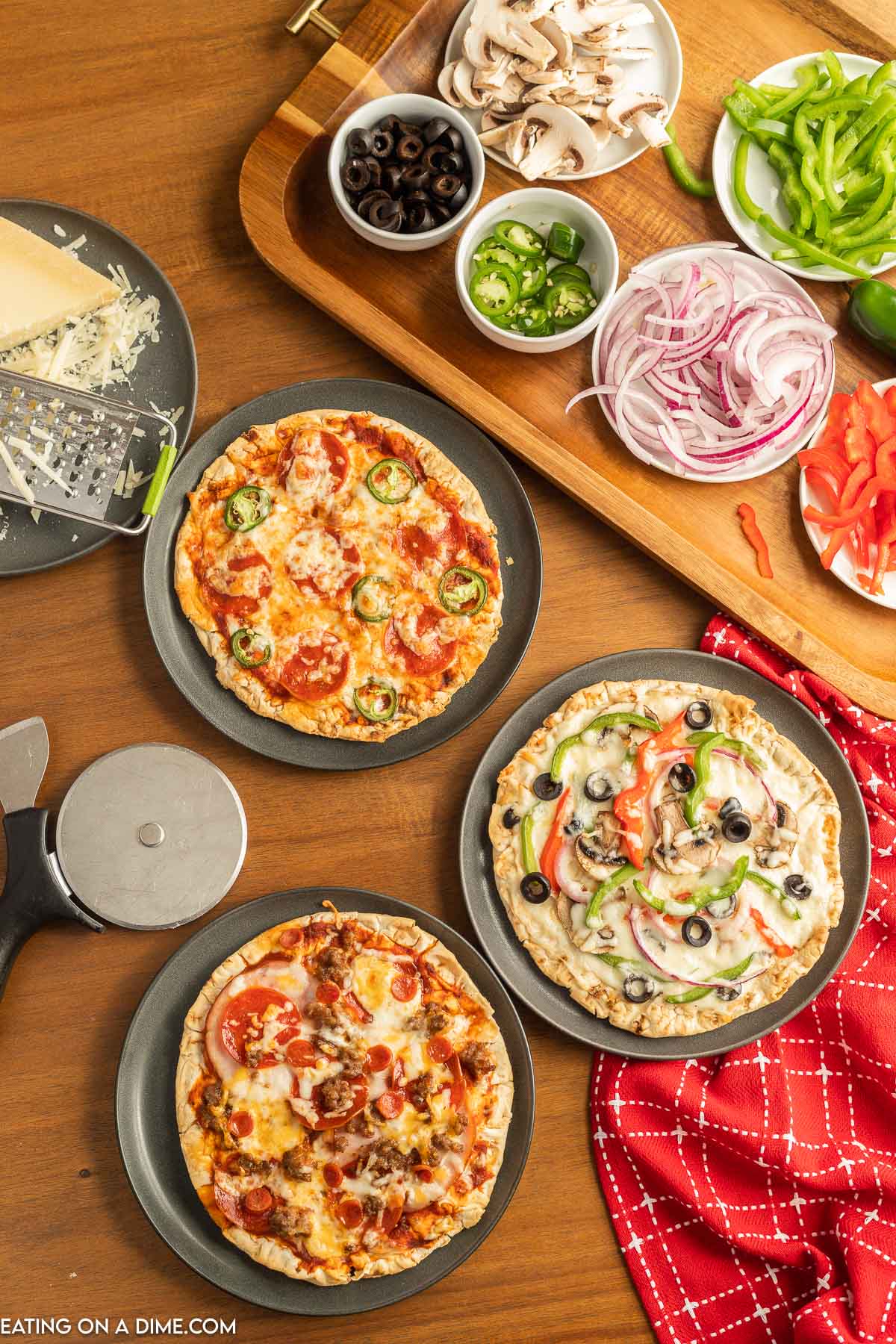 Pizzas on plates with a bowls of different pizza toppings