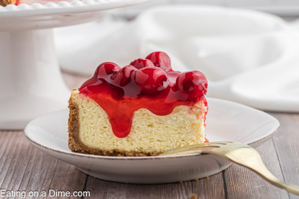 A slice of cheesecake on a plate topped with cherry
