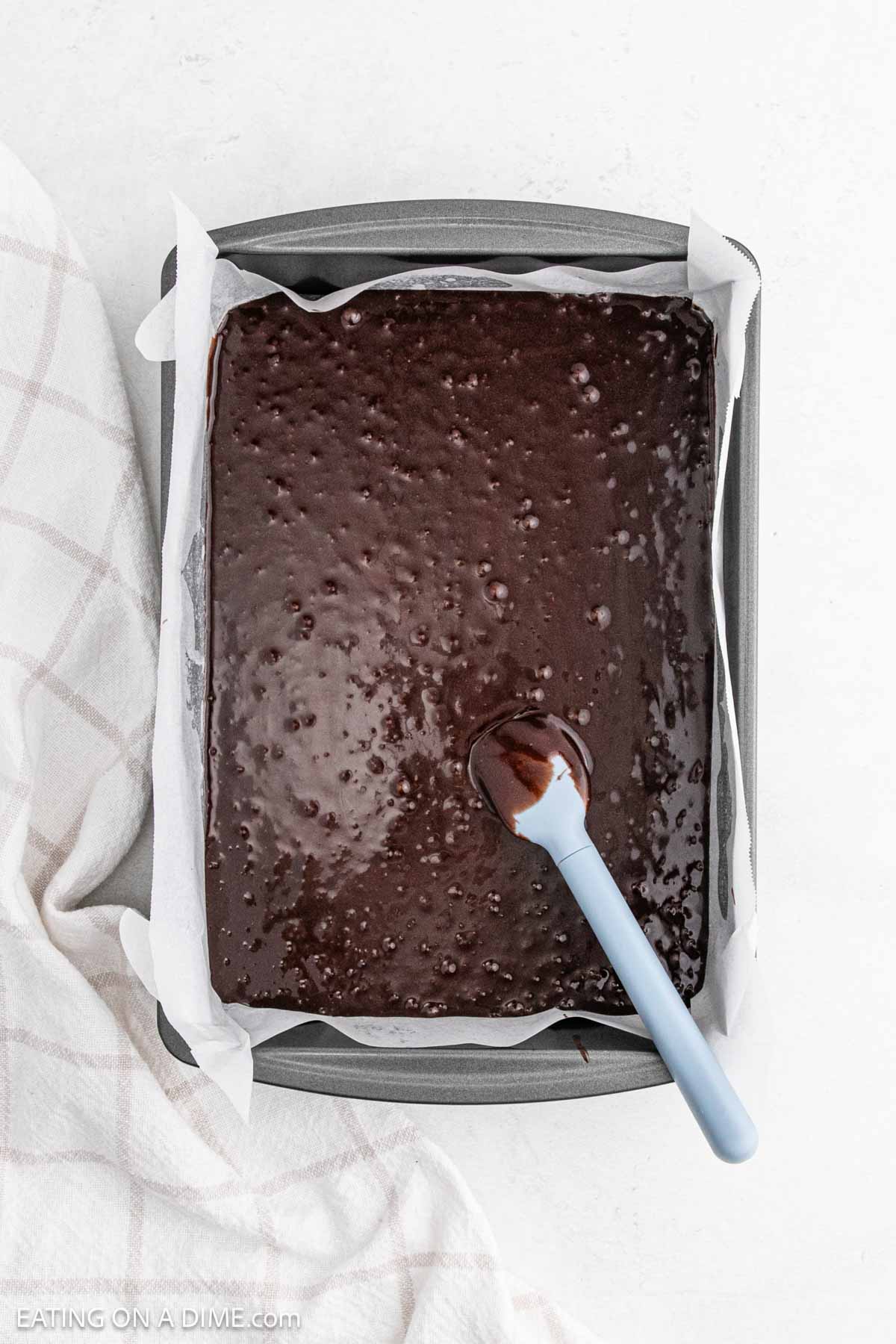 Brownie Batter in a baking pan lined with parchment paper 