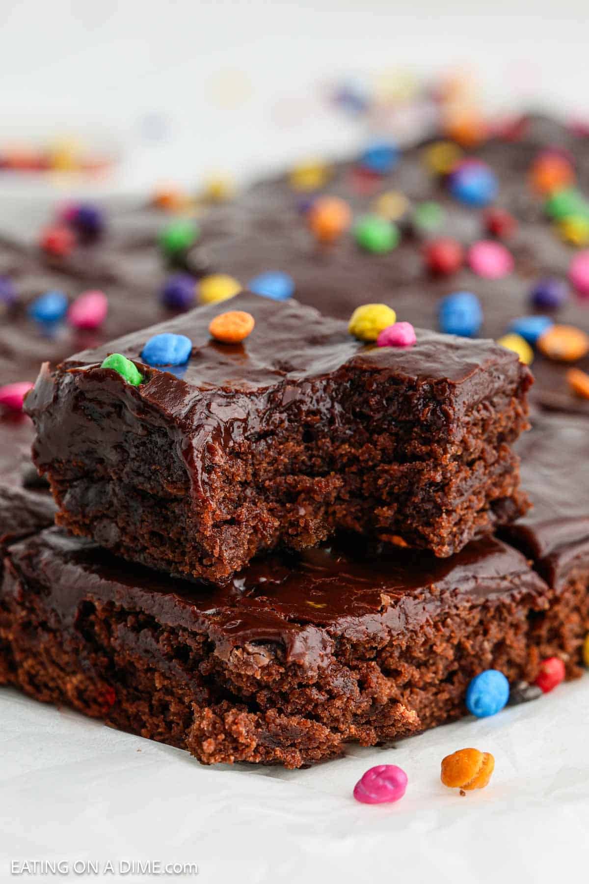 Cosmic Brownies cut into squares stacked and topped with rainbow colored chocolate chips