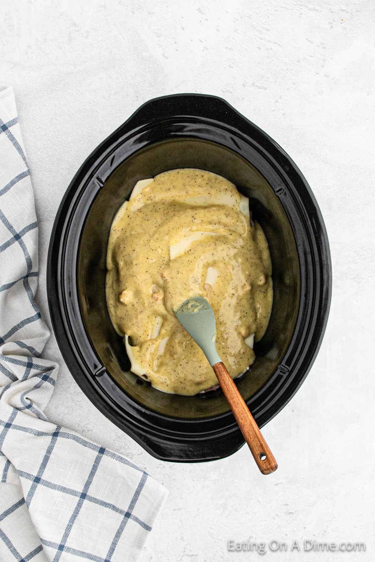 Spreading cream of chicken soup on the chicken in the slow cooker