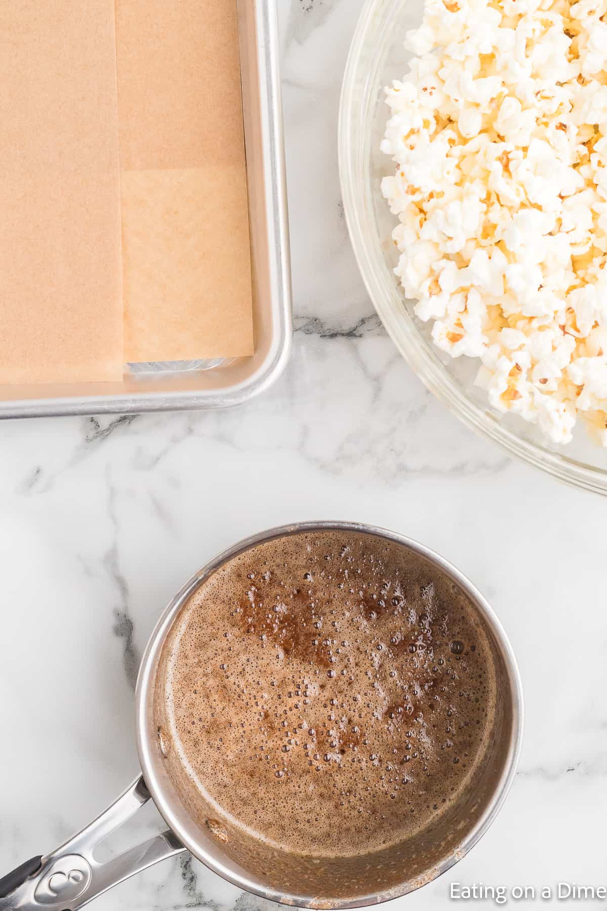 Cinnamon mixture boiling in a saucepan with a bowl of popcorn on the side