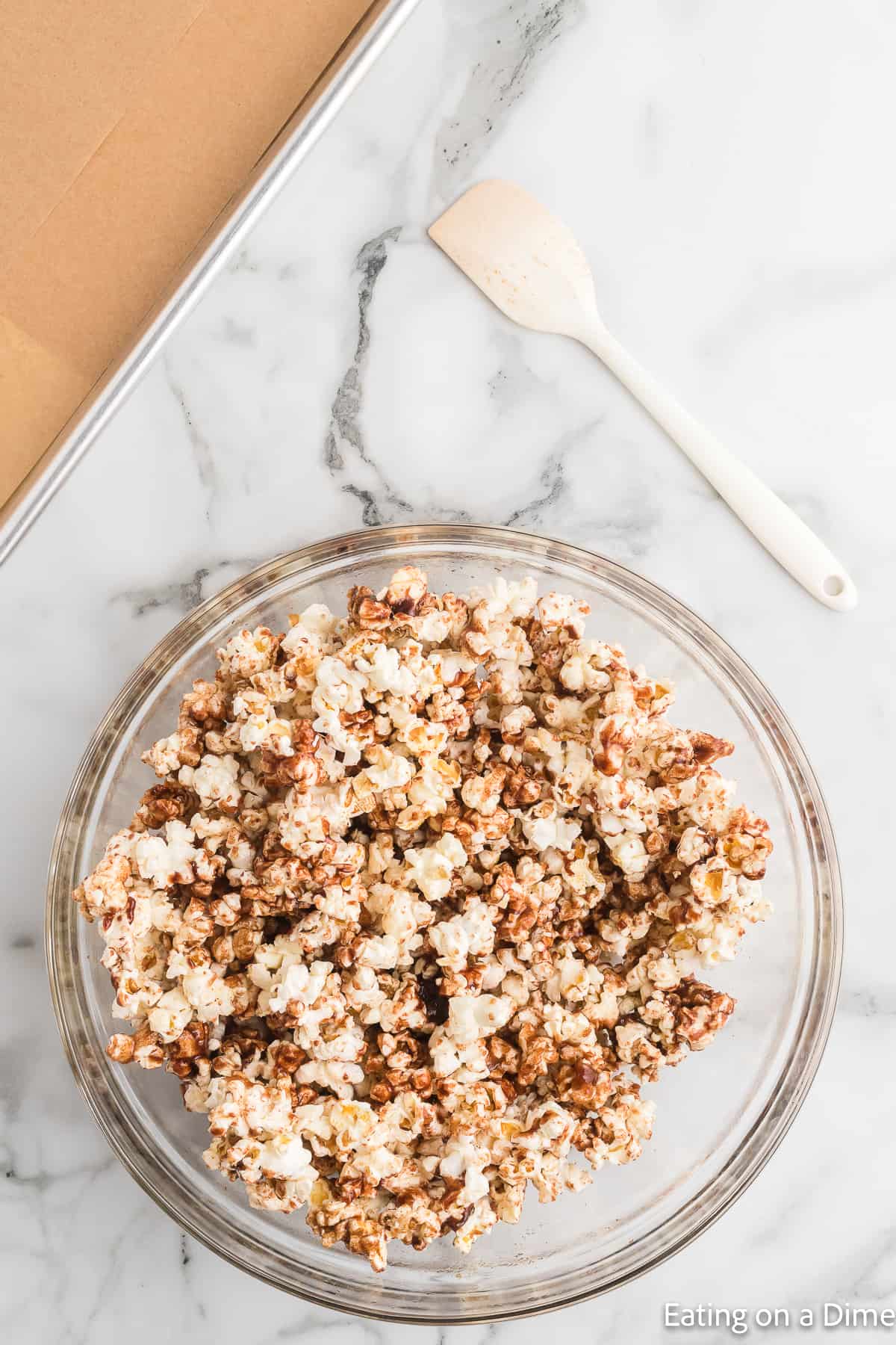 Cinnamon mixture poured over the popcorn in a bowl