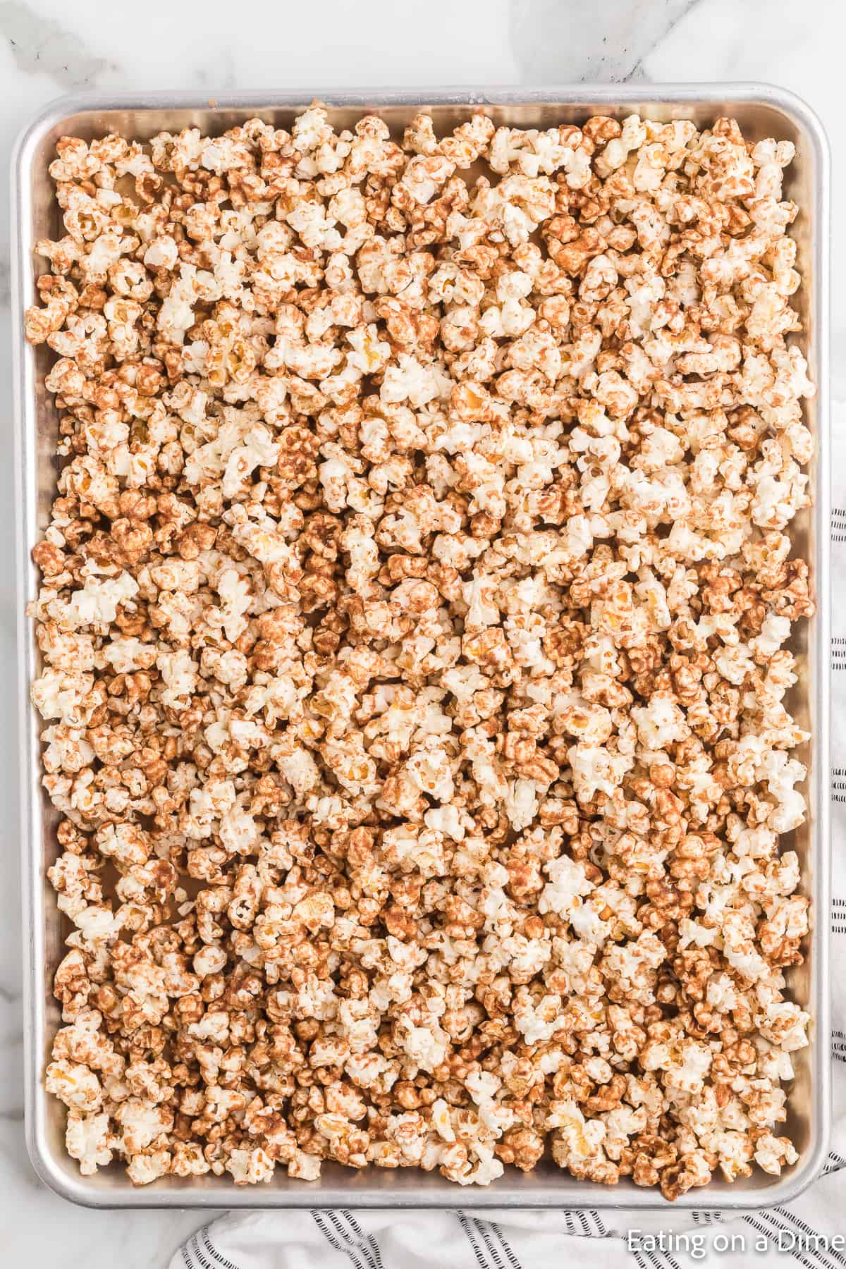 Cinnamon popcorn spread out in a baking sheet