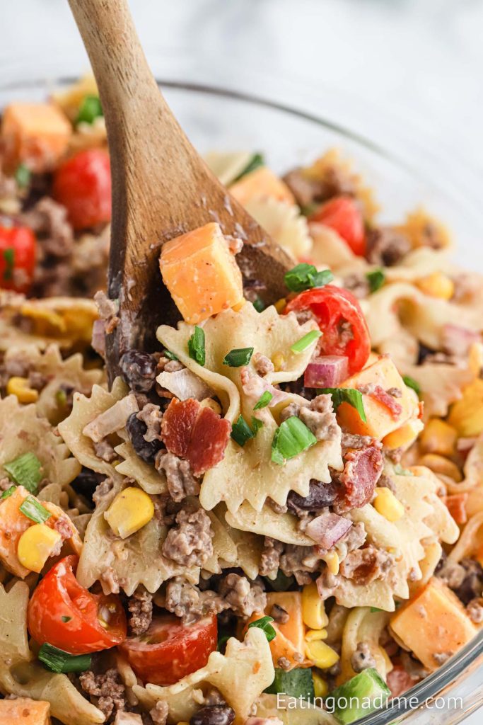 Cowboy Pasta Salad in a white bowl with a wooden spoon