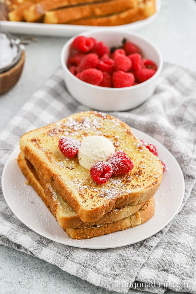 French Toast on a plate topped with raspberries and butter
