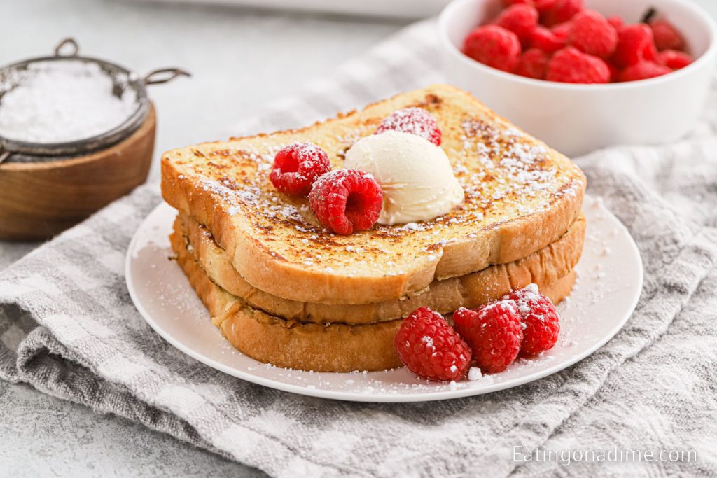 French Toast on a plate topped with raspberries and butter